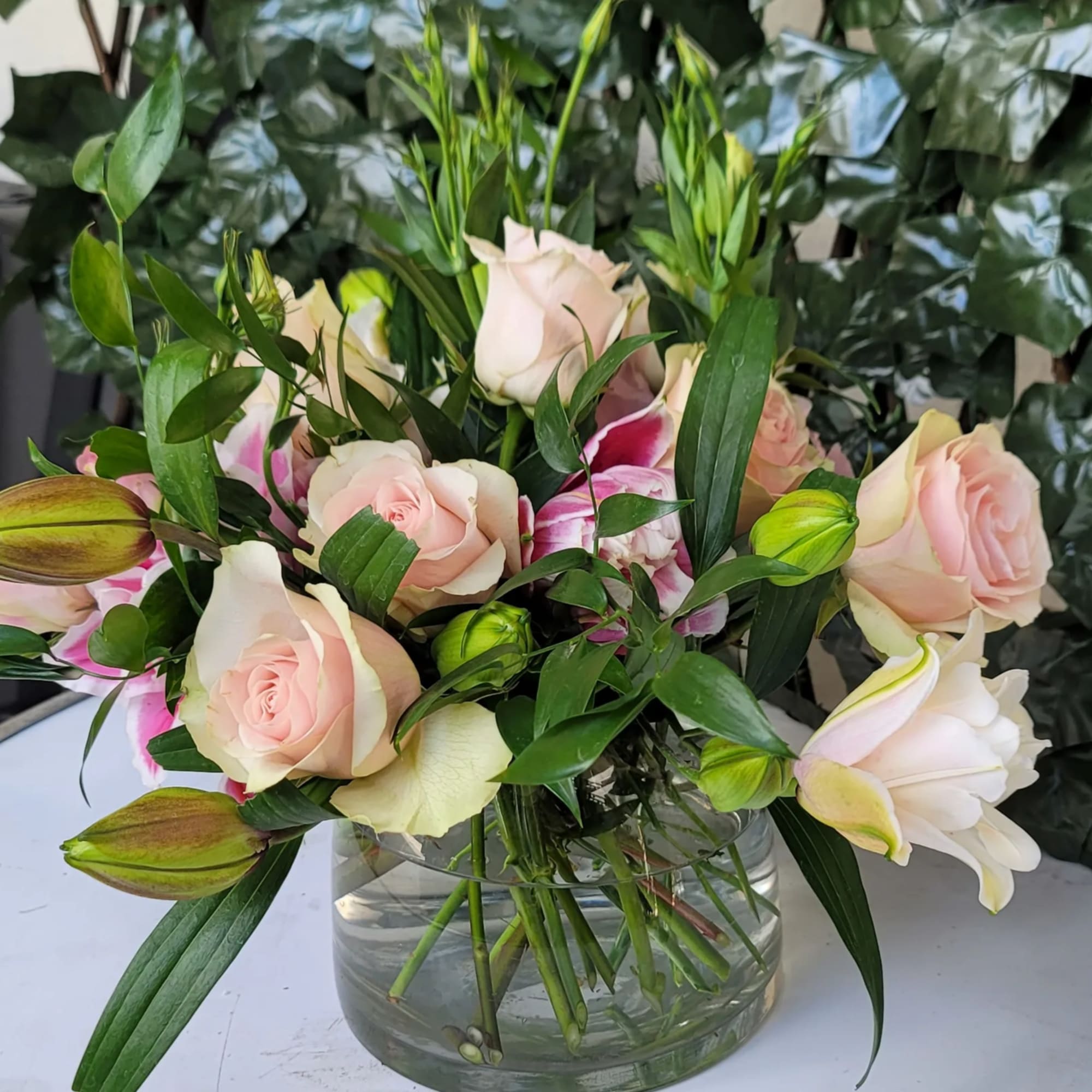 Pink roses and white lilies arranged in a clear glass vase