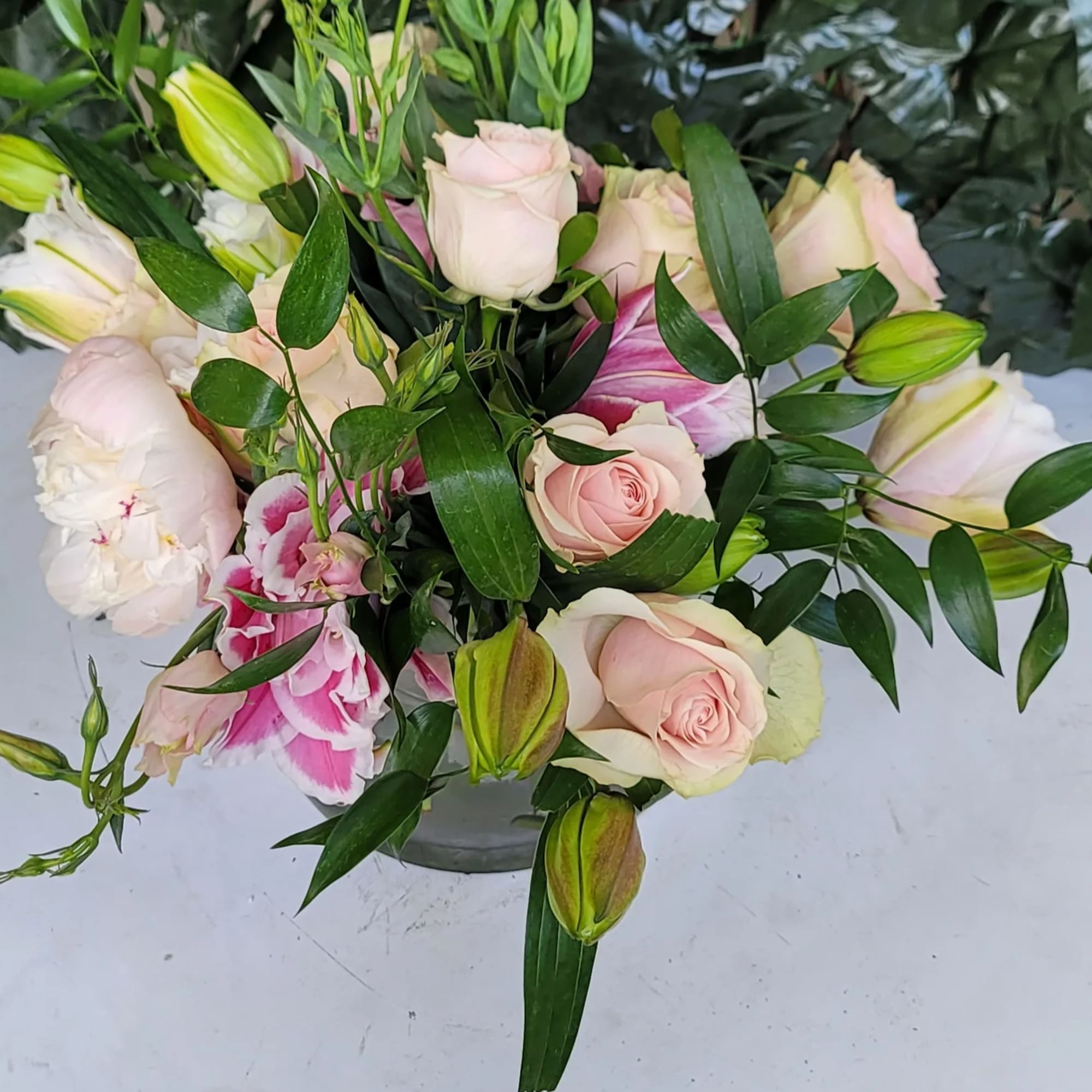 Pink roses and lilies arranged in a low glass vase