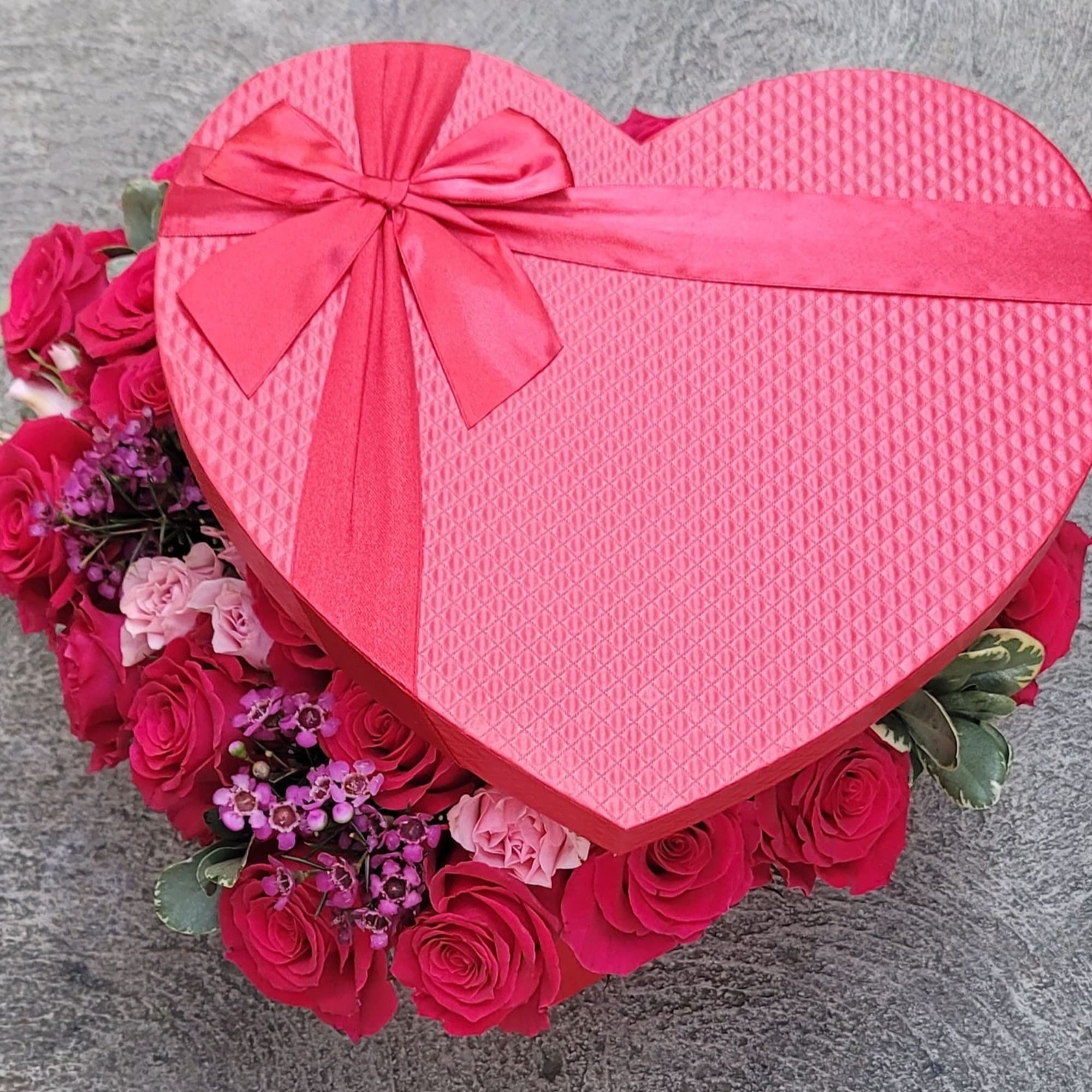 Heart-shaped pink gift box with roses and small purple flowers