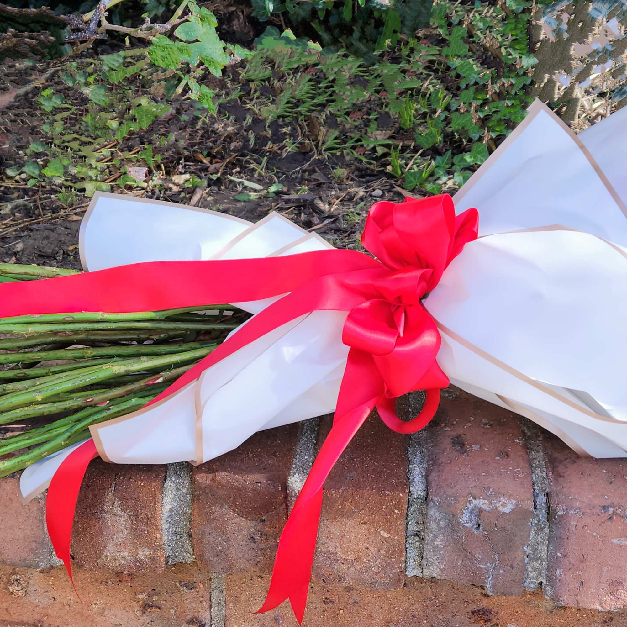 Wrapped bouquet with red ribbon lying on brick steps