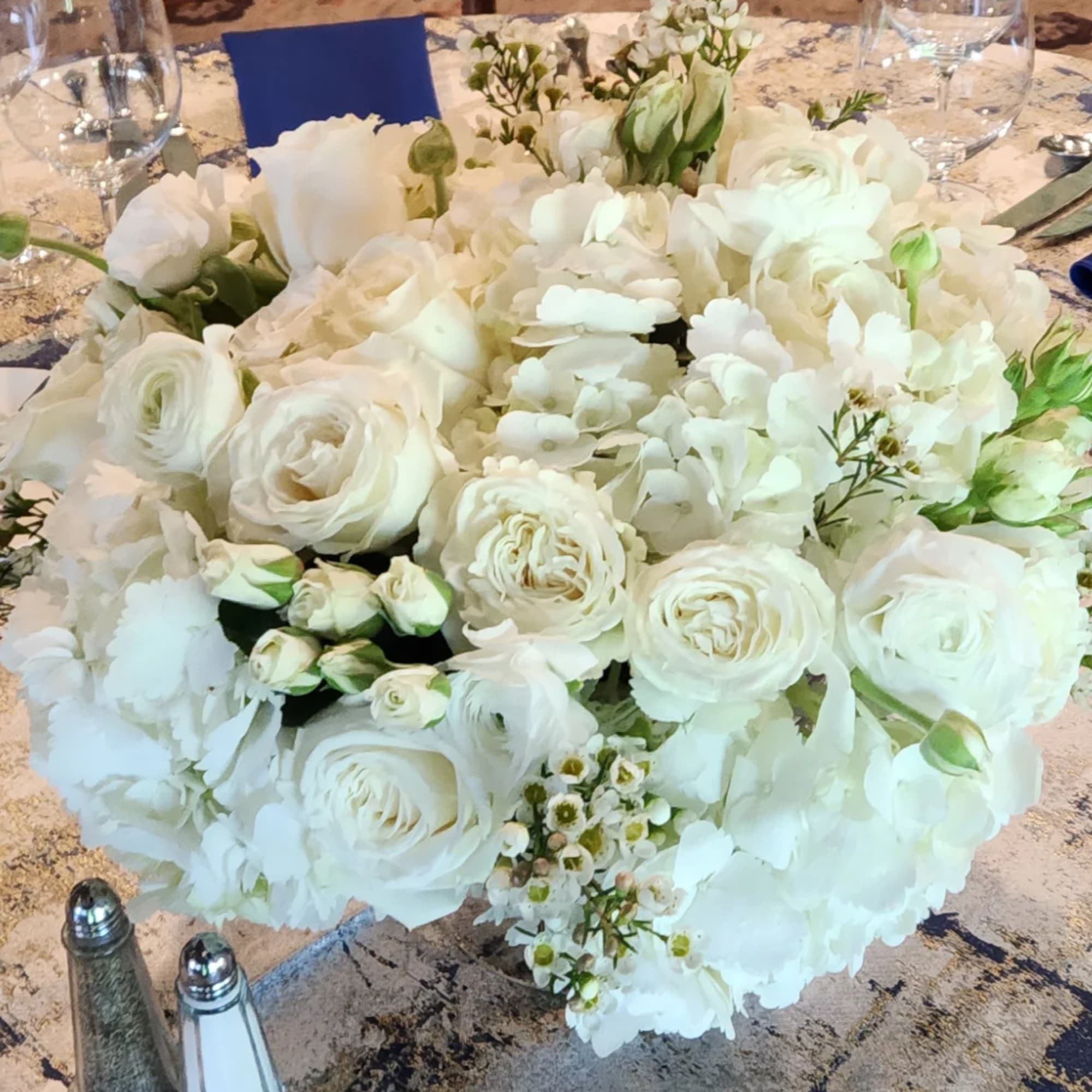 White floral centerpiece with roses and hydrangeas on a set table