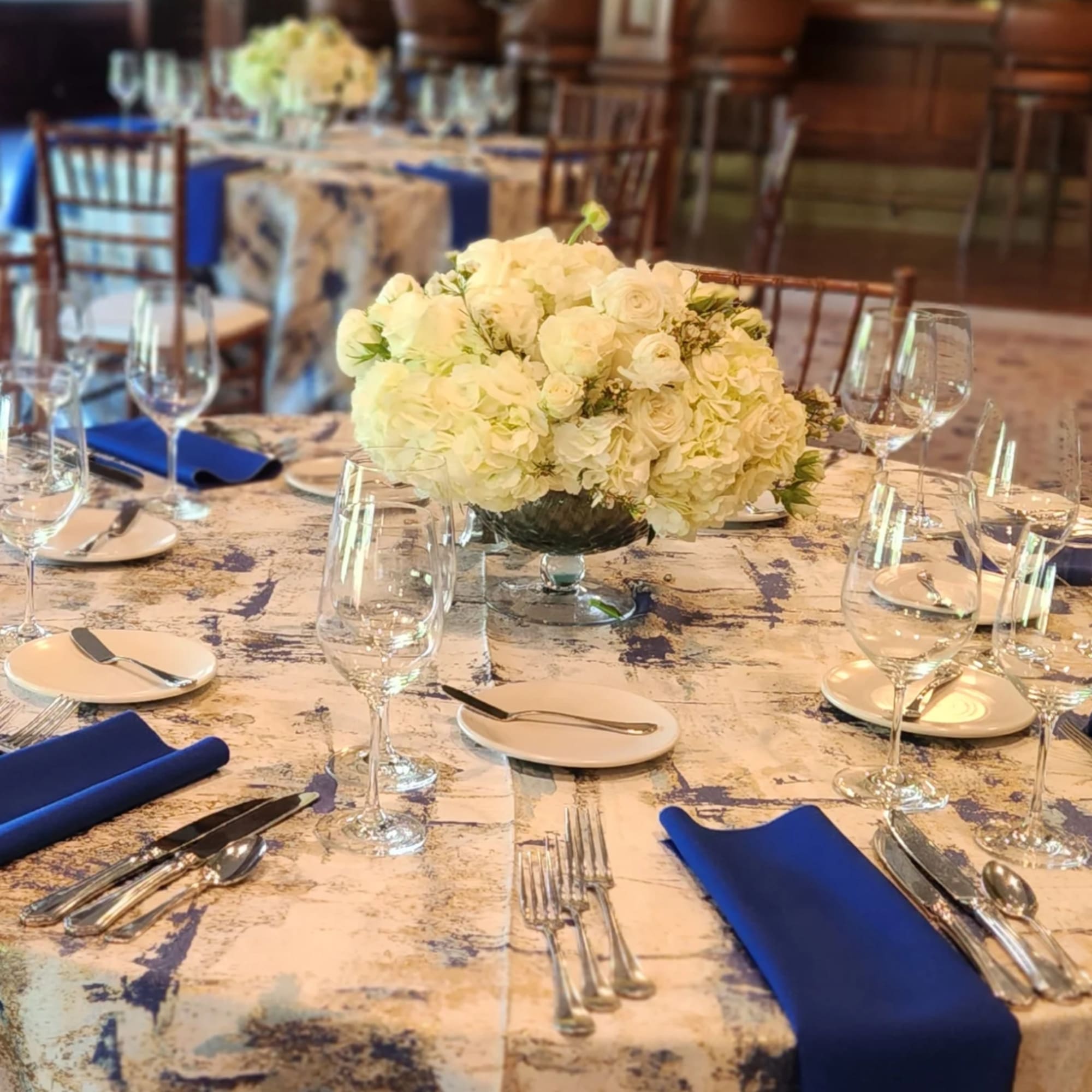Round banquet table with white floral centerpiece and blue napkins