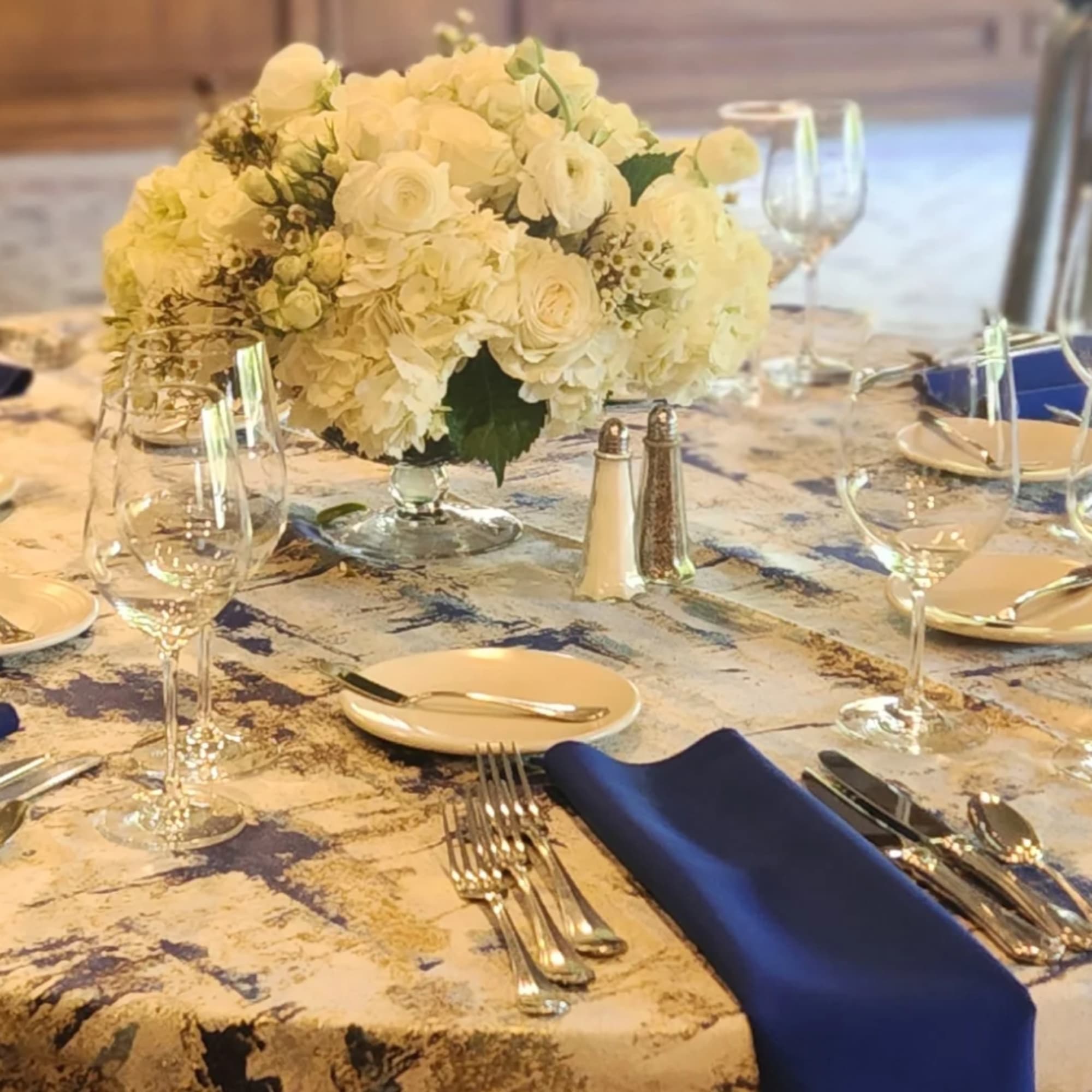 Round table with a white floral centerpiece and navy napkins