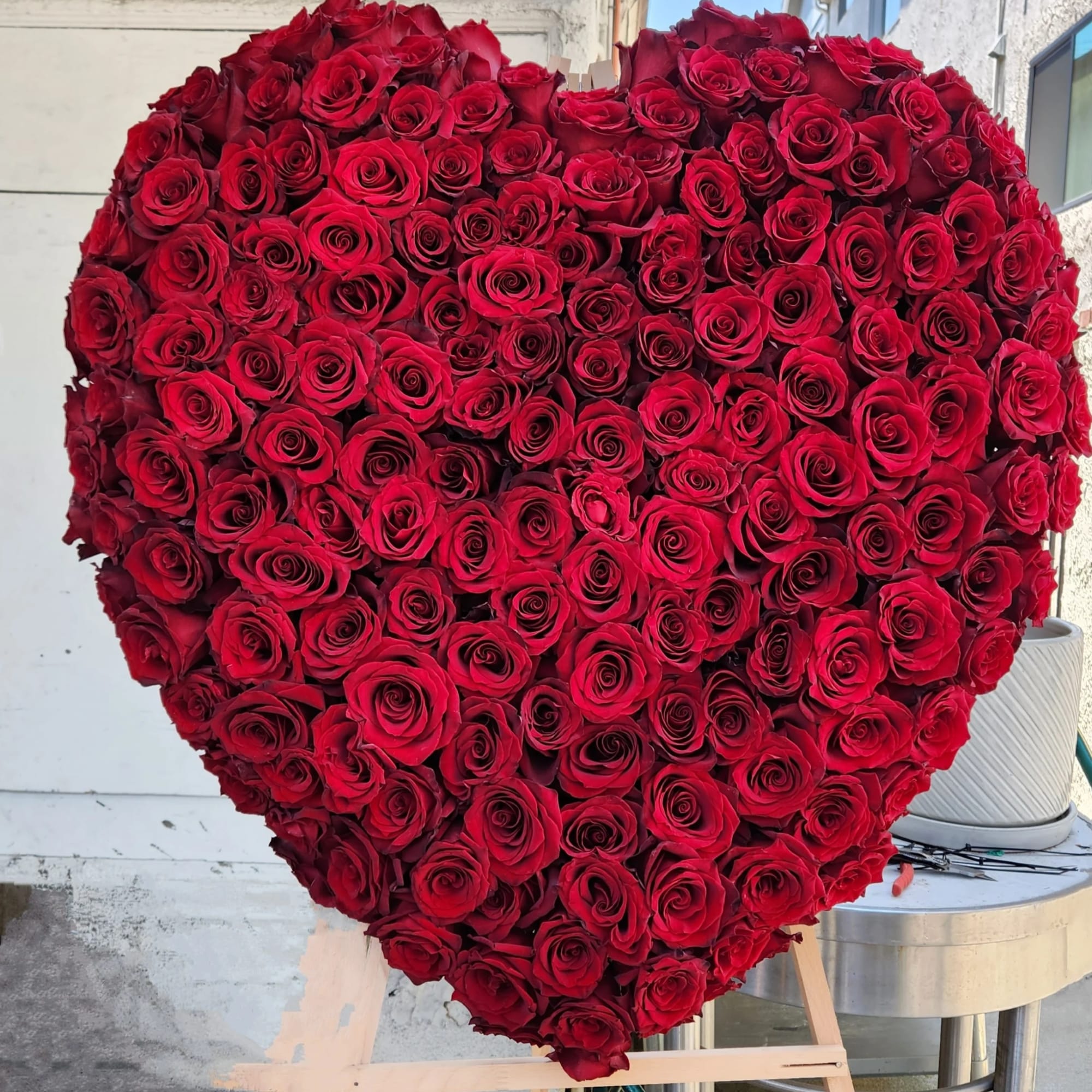Large heart-shaped arrangement of red roses on an easel
