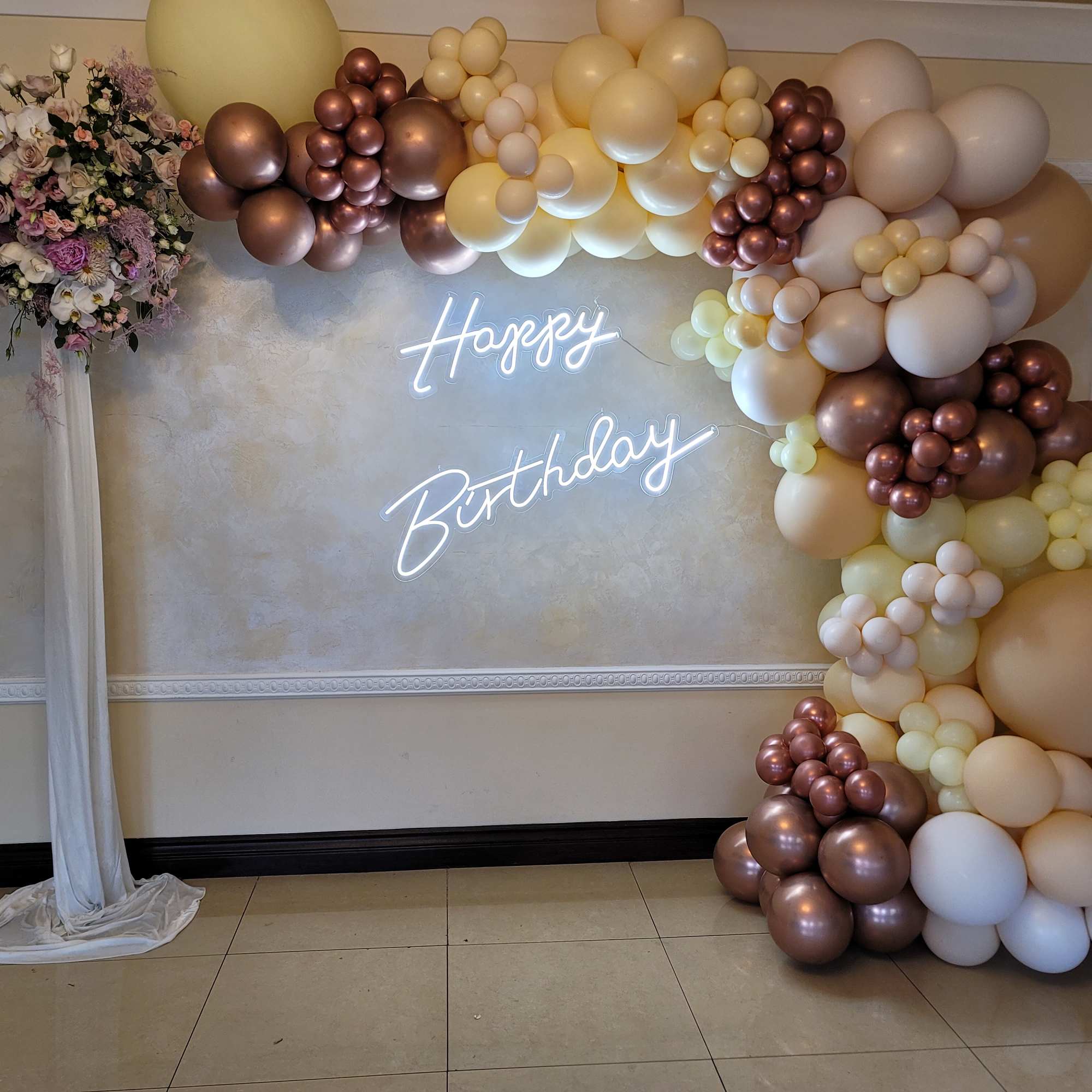Birthday backdrop with balloon garland and a floral arrangement