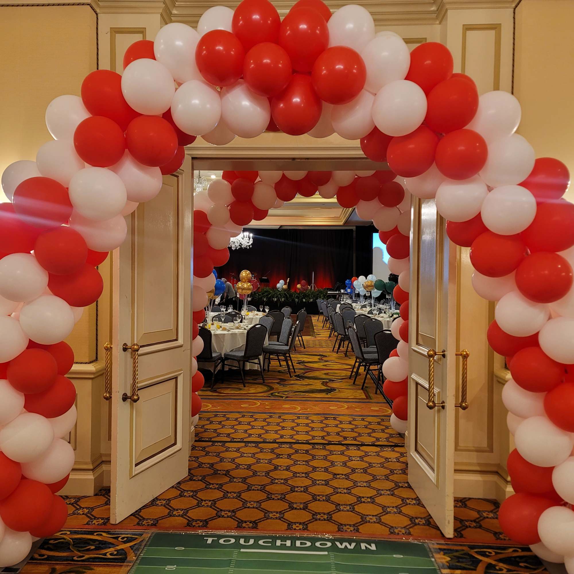 Red and white balloon arch framing open double doors