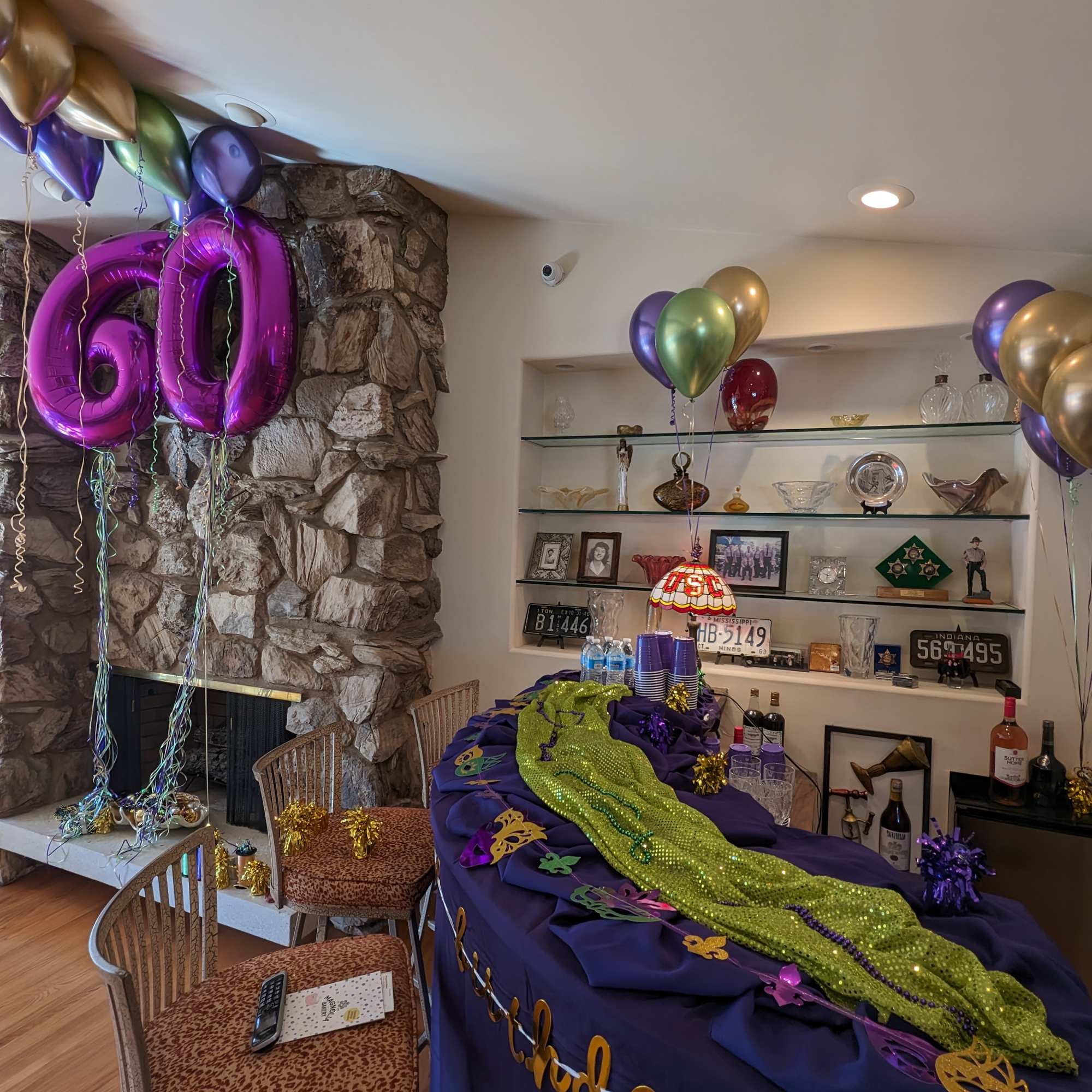 Mardi Gras party setup with balloons, table decor, and a "60" balloon display