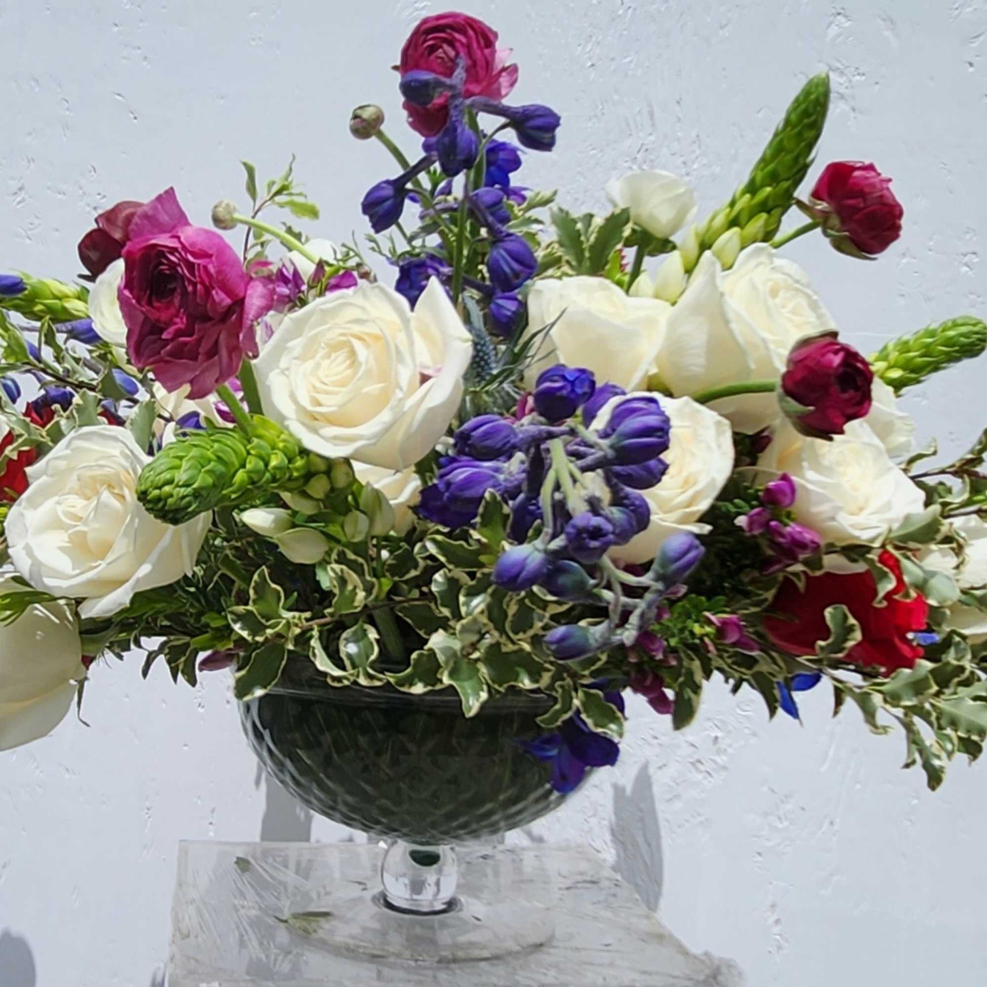 Mixed bouquet of white roses, purple flowers, and red blooms in a glass vase