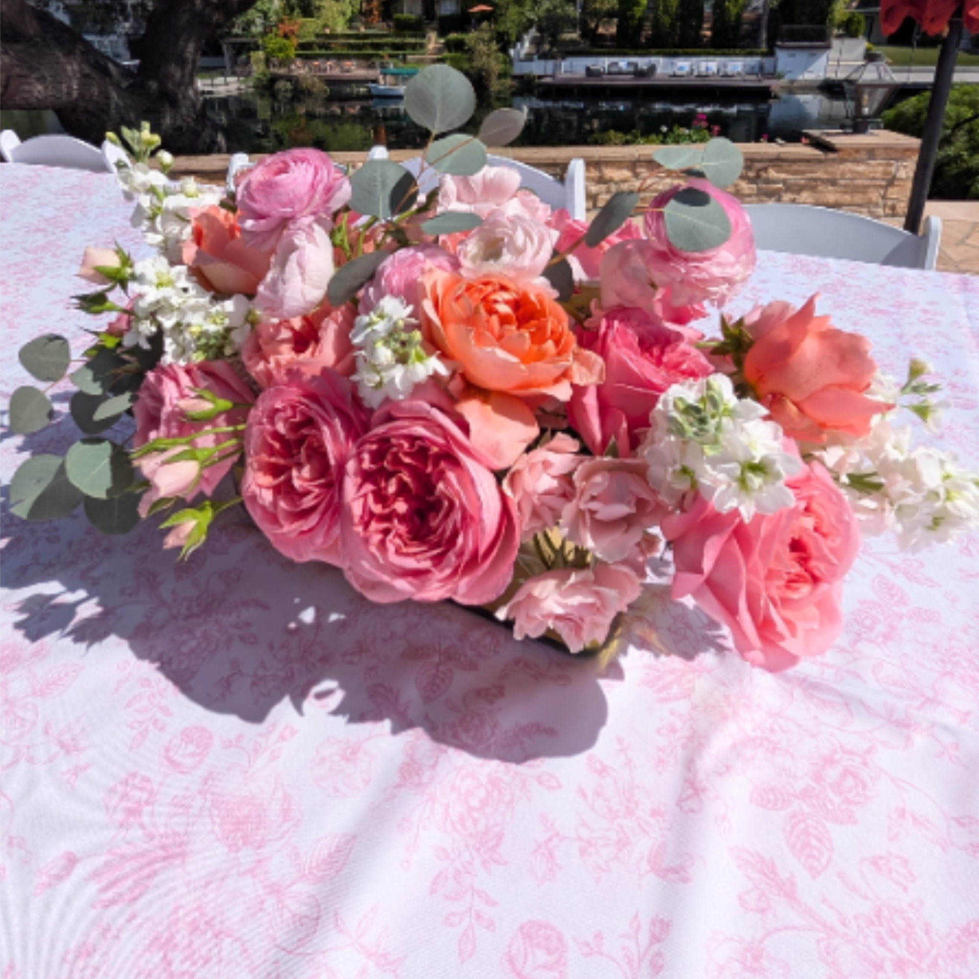 Lush, low-profile centerpiece of roses, ranunculus, &amp; silver dollar eucalyptus