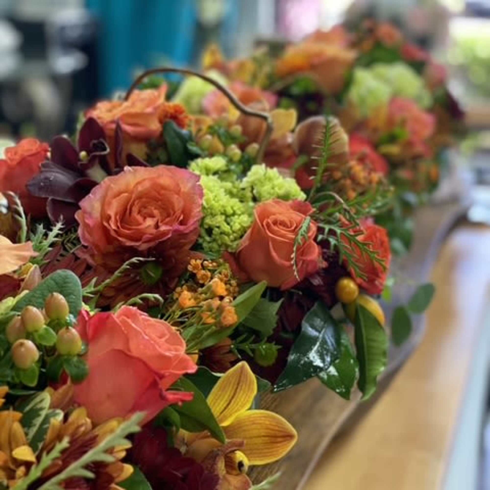 Bouquets of orange roses and mixed flowers arranged in a basket