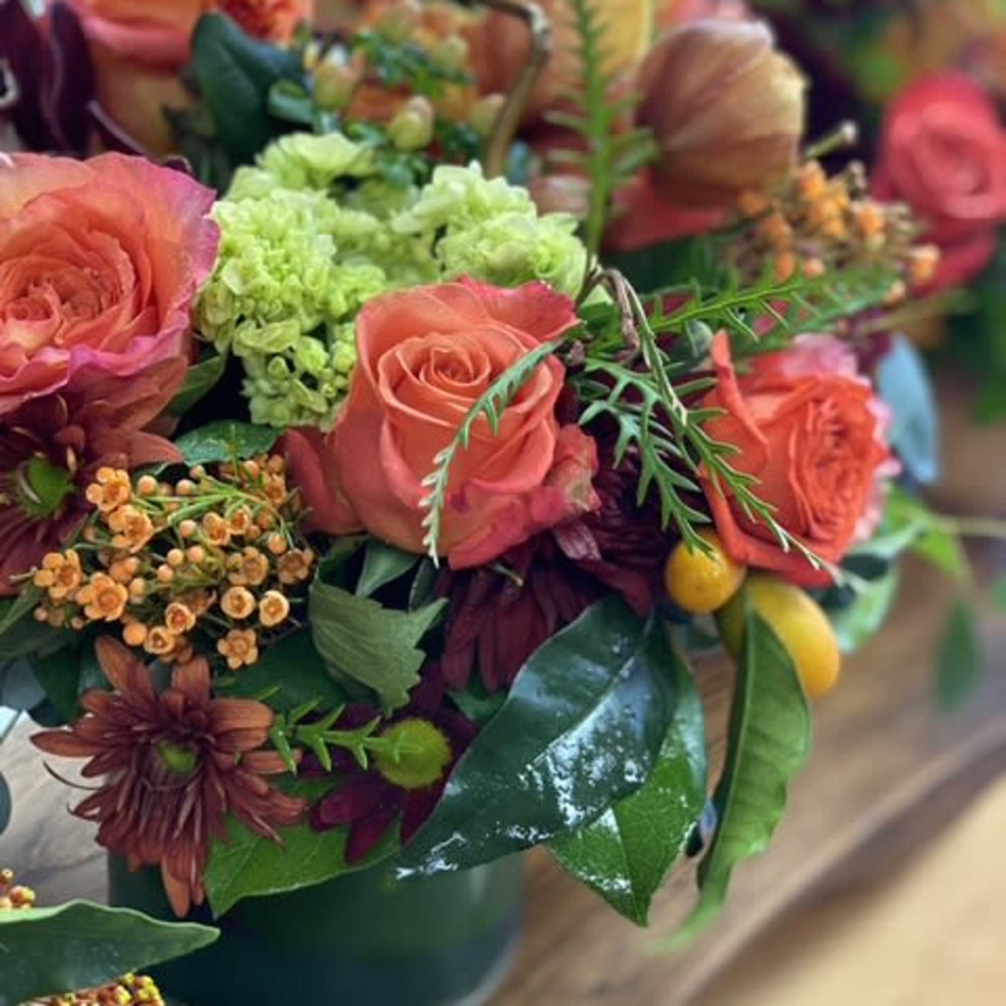 Coral roses and green hydrangeas in a dark vase