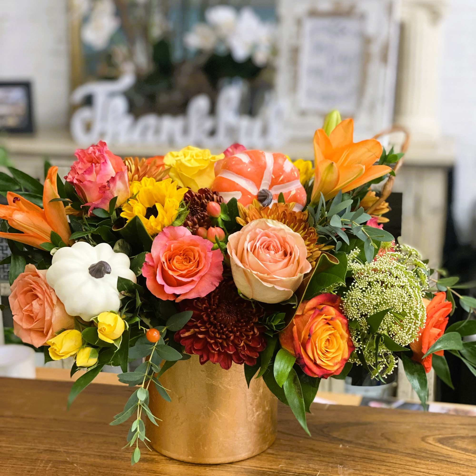 Beautiful golden cylinder filled uniquely with warm fall flowers and topped with