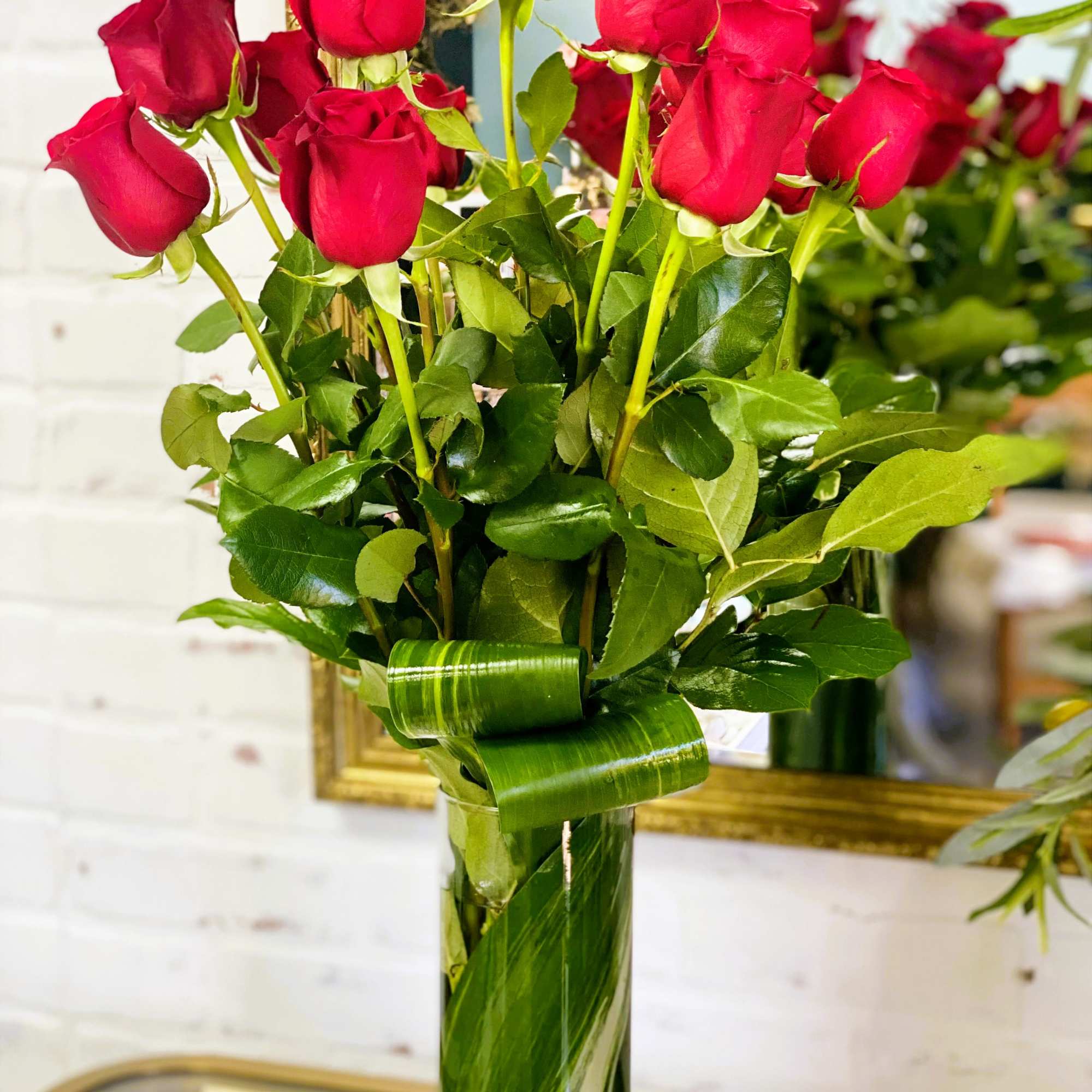 Bouquet of red roses in a clear glass vase with a green ribbon