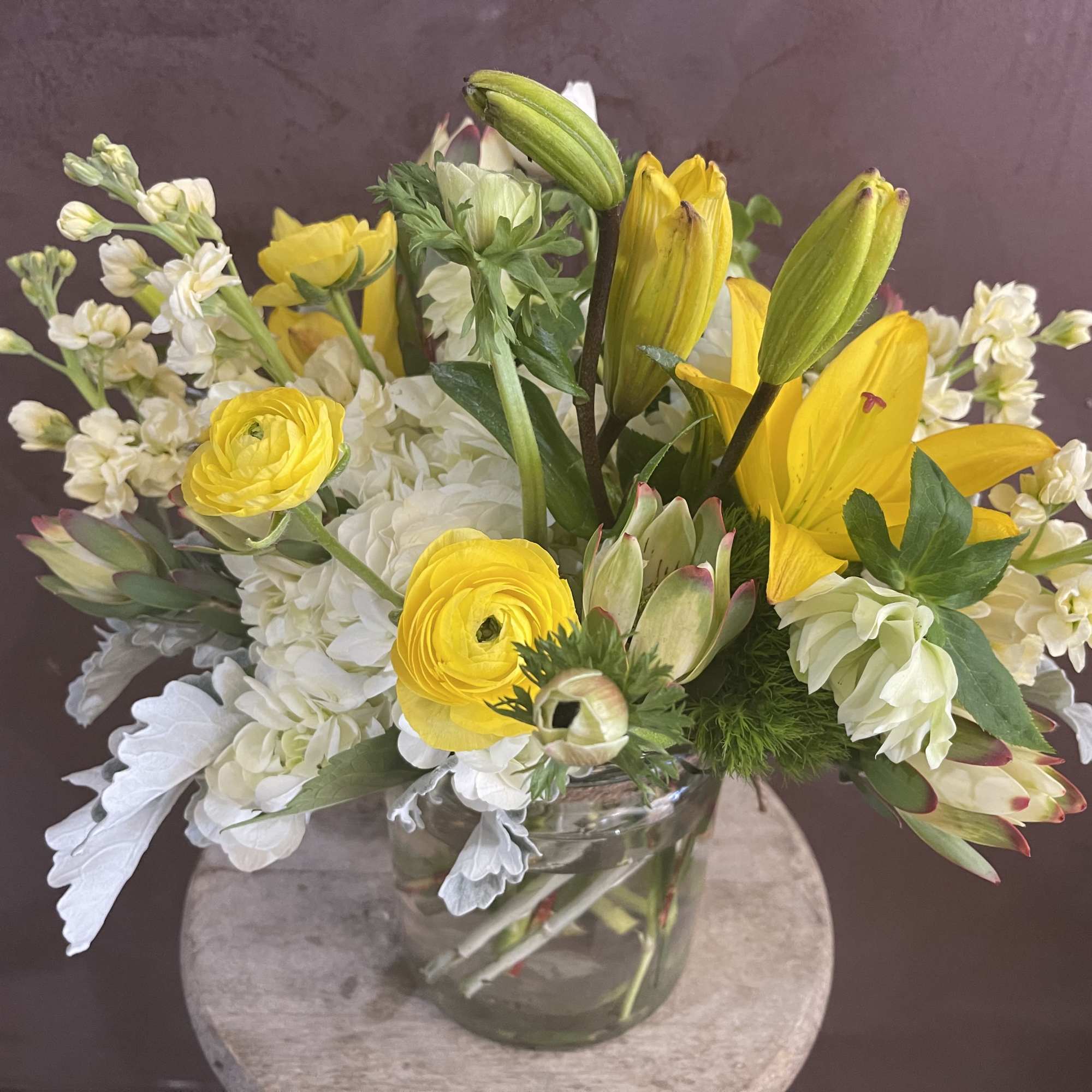 Yellow lilies and white flowers in a clear glass vase