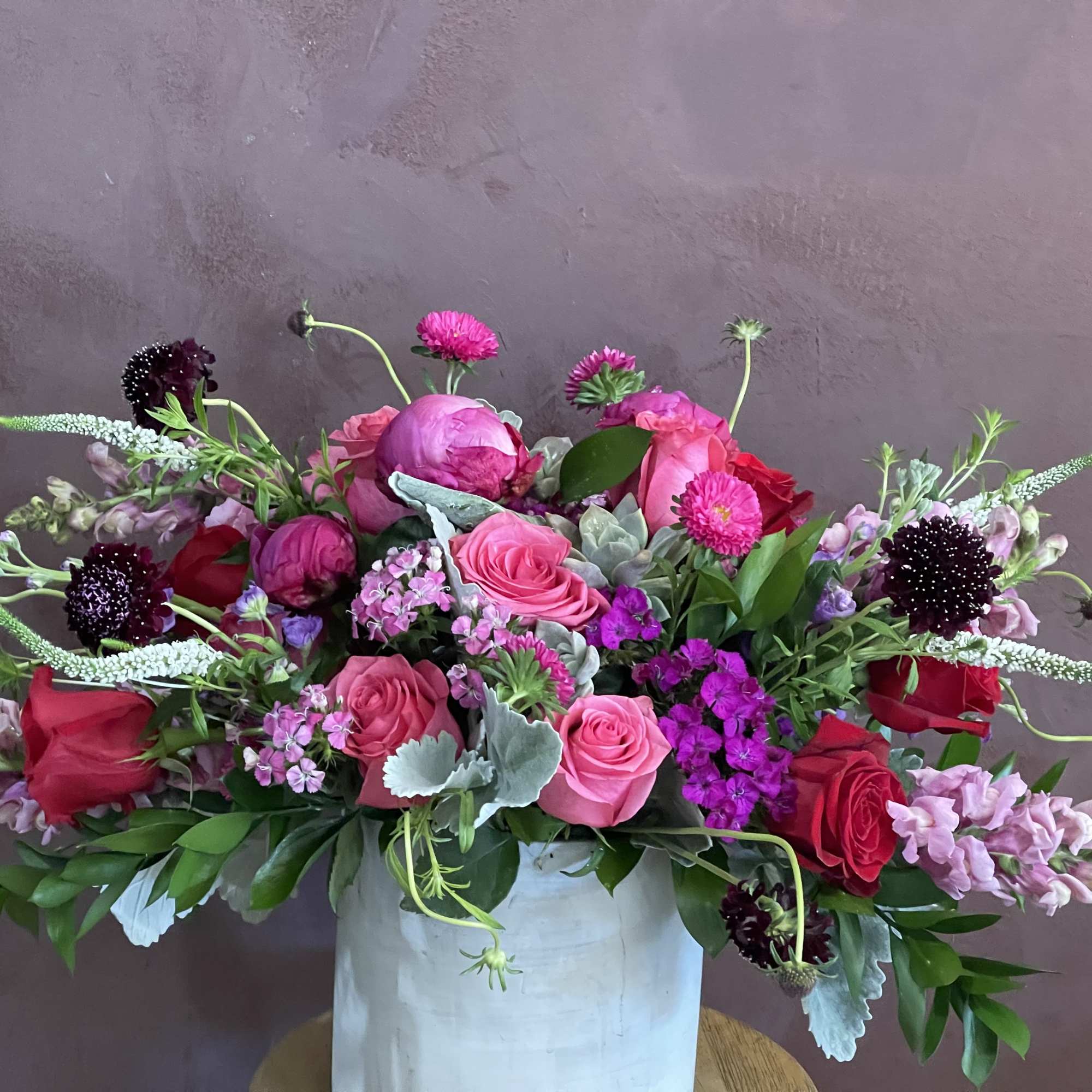 Pink and red mixed flower arrangement in a white vase