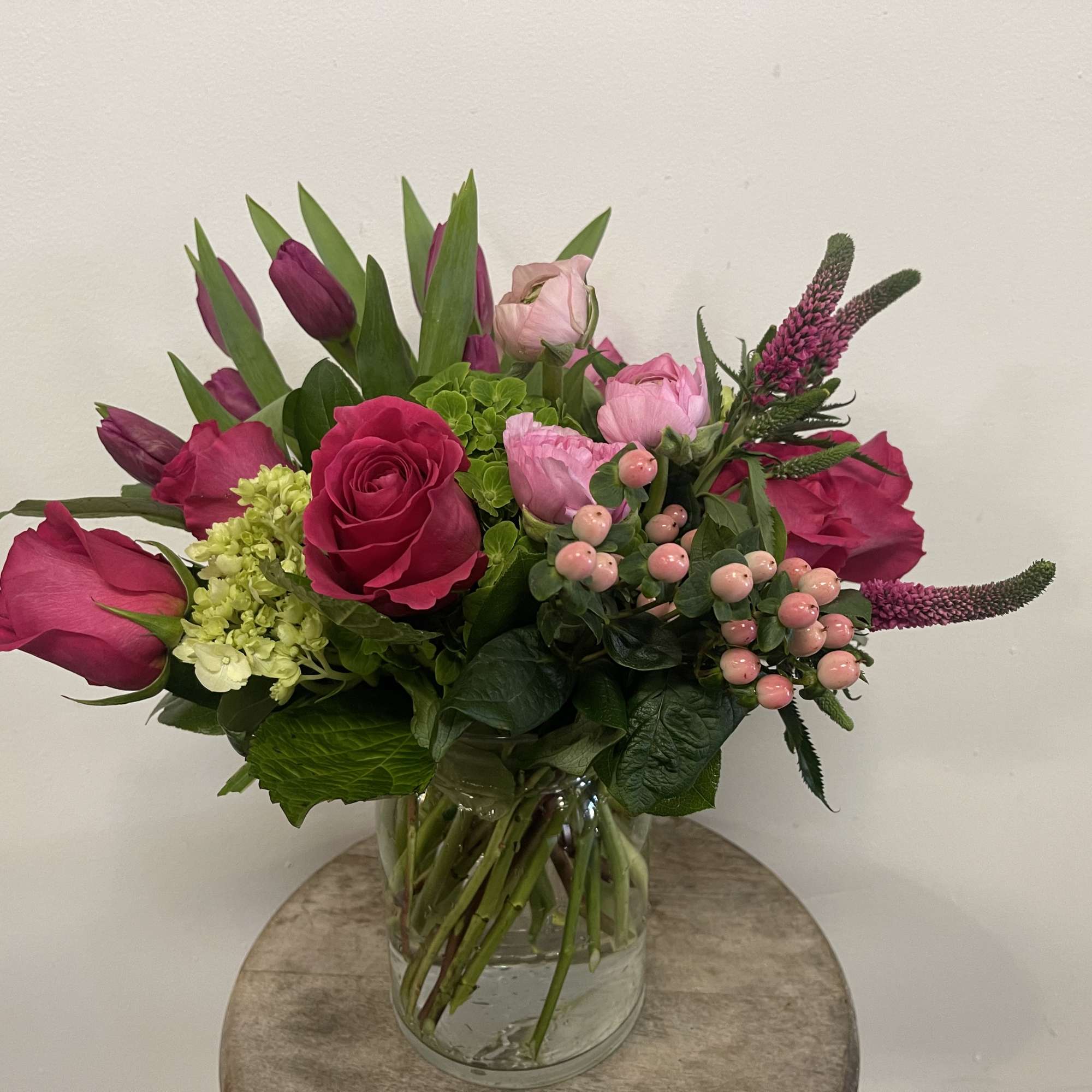 Pink roses and tulips arranged in a glass vase