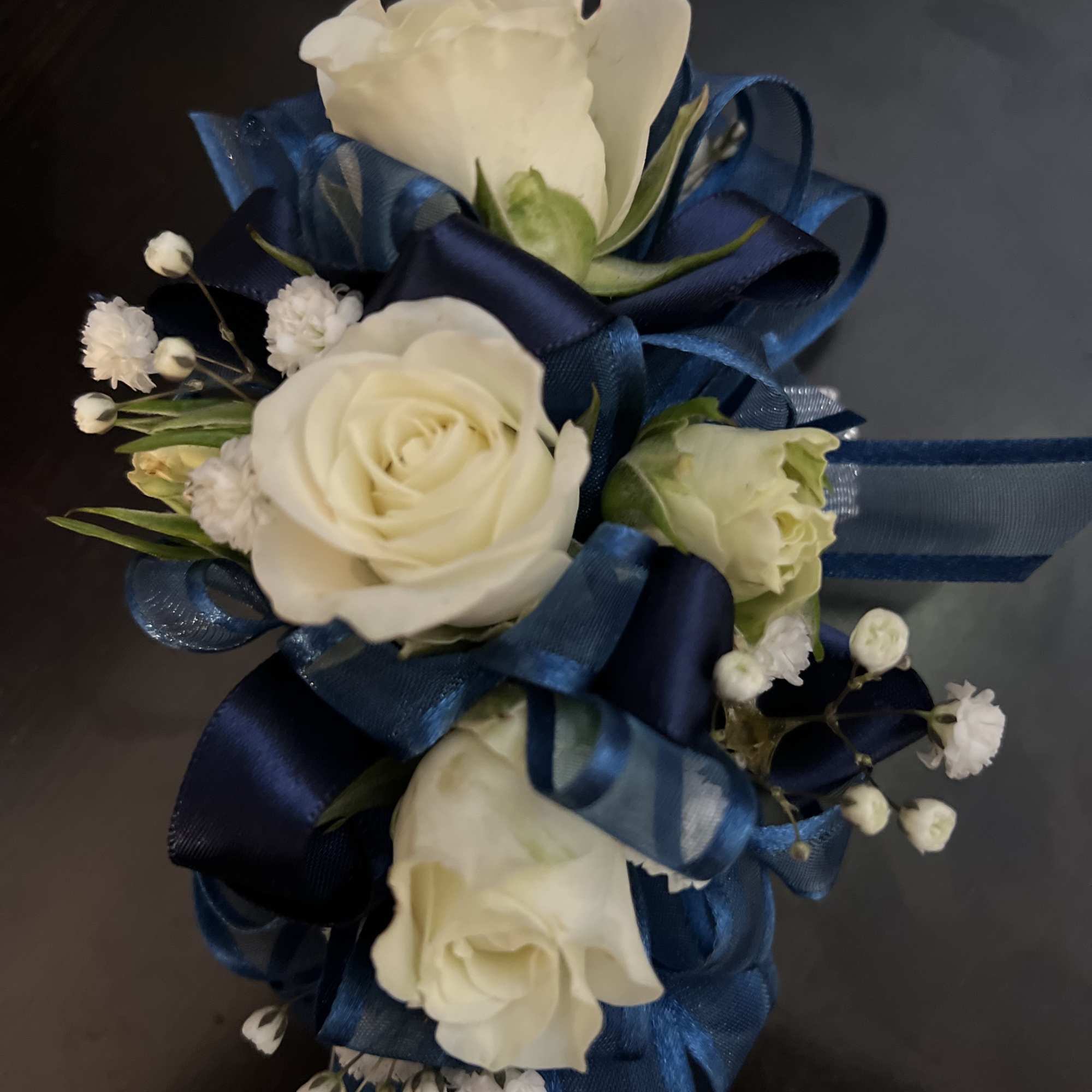 White rose corsage with blue ribbon and small white filler flowers