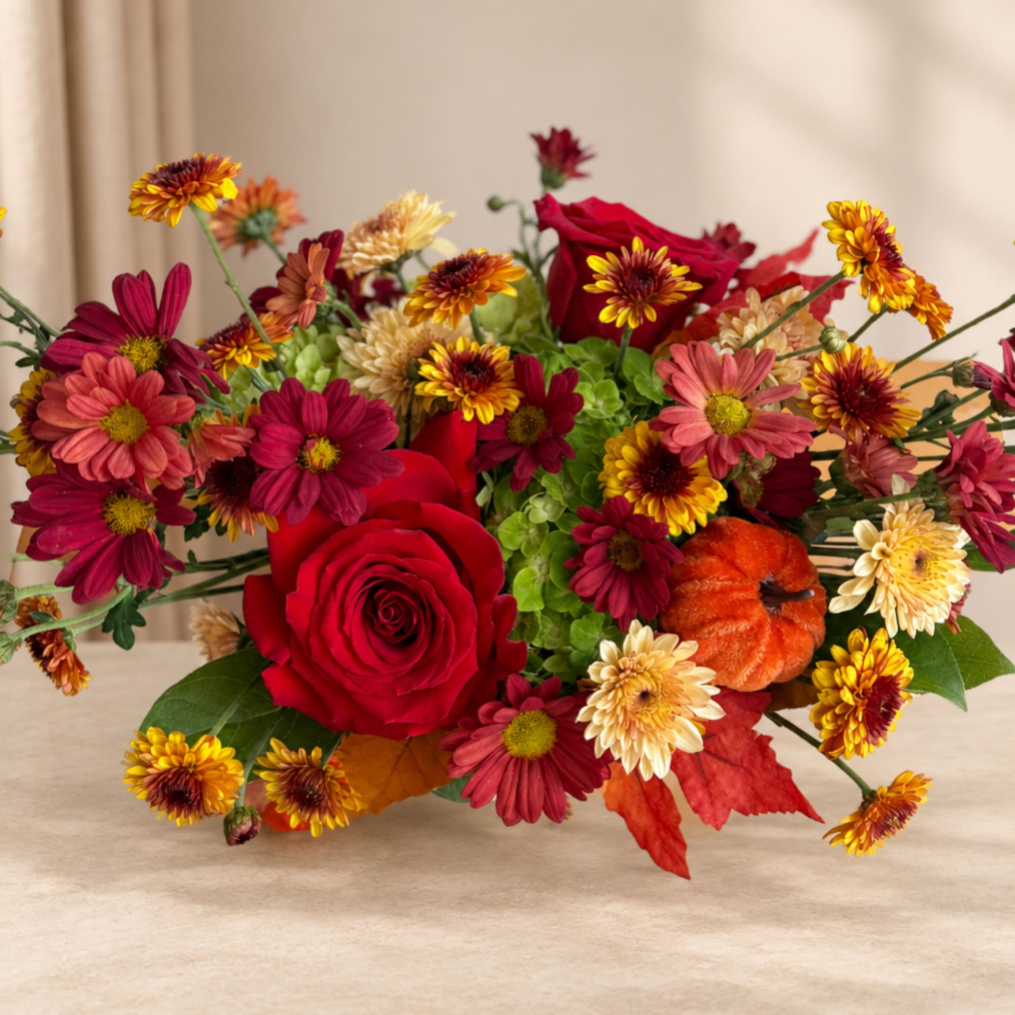 Bouquet of red roses and mixed autumn flowers on a light surface