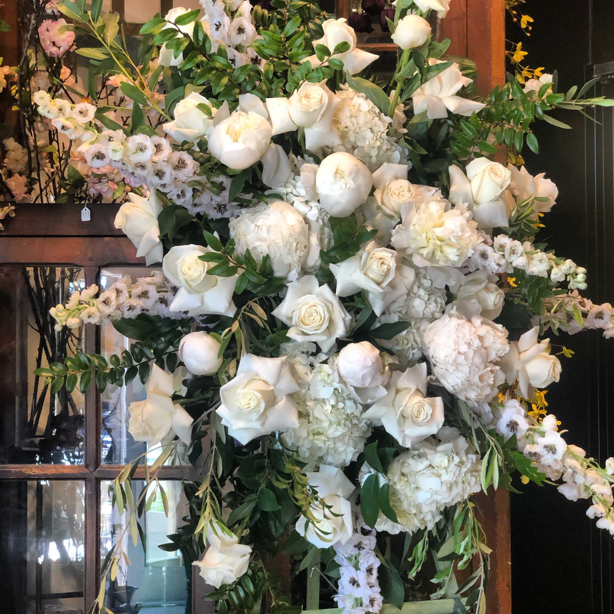 Large white floral arrangement with roses, peonies, and orchids