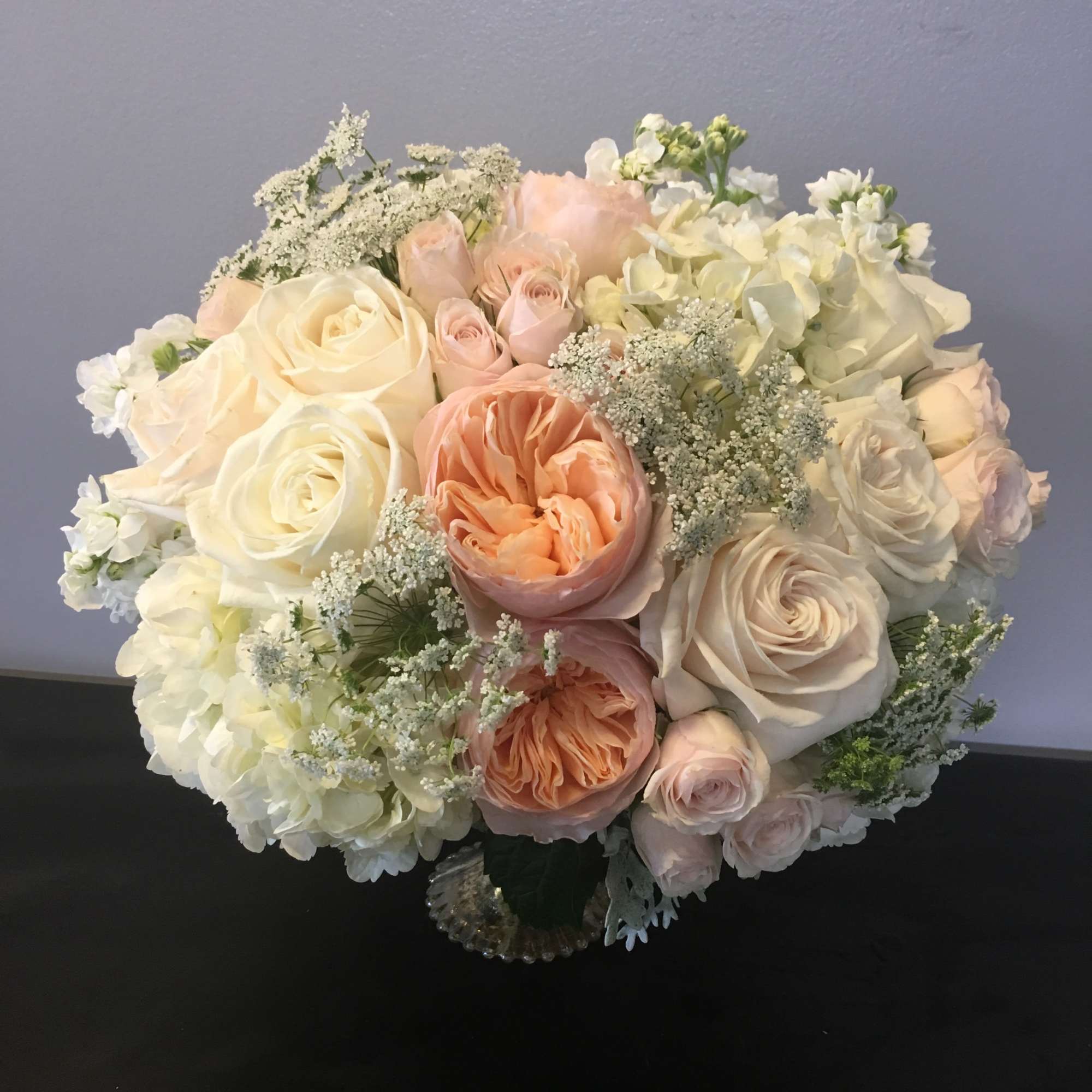 Bouquet of cream, blush, and peach roses with white hydrangeas