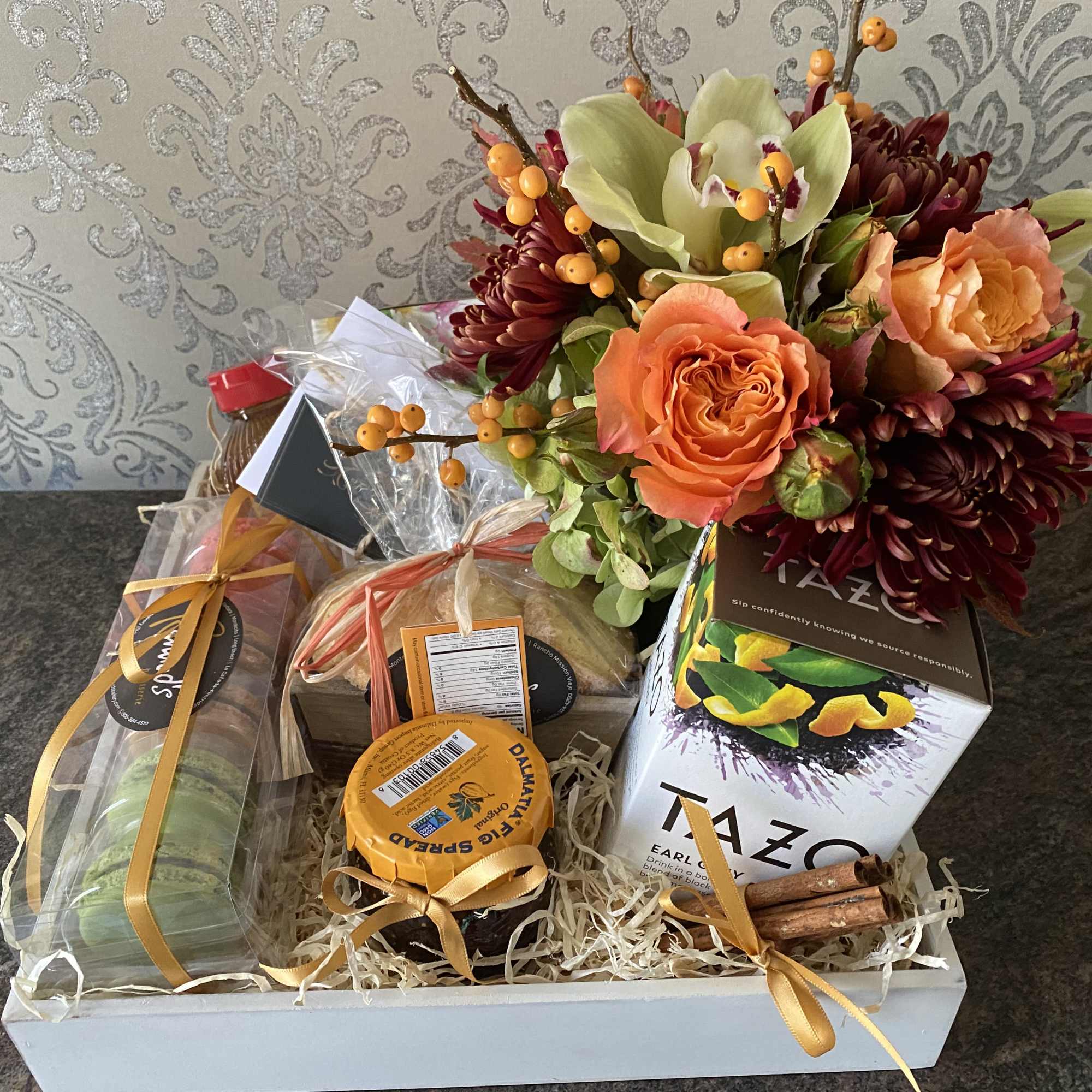 Gift basket with flowers, tea boxes, and packaged treats