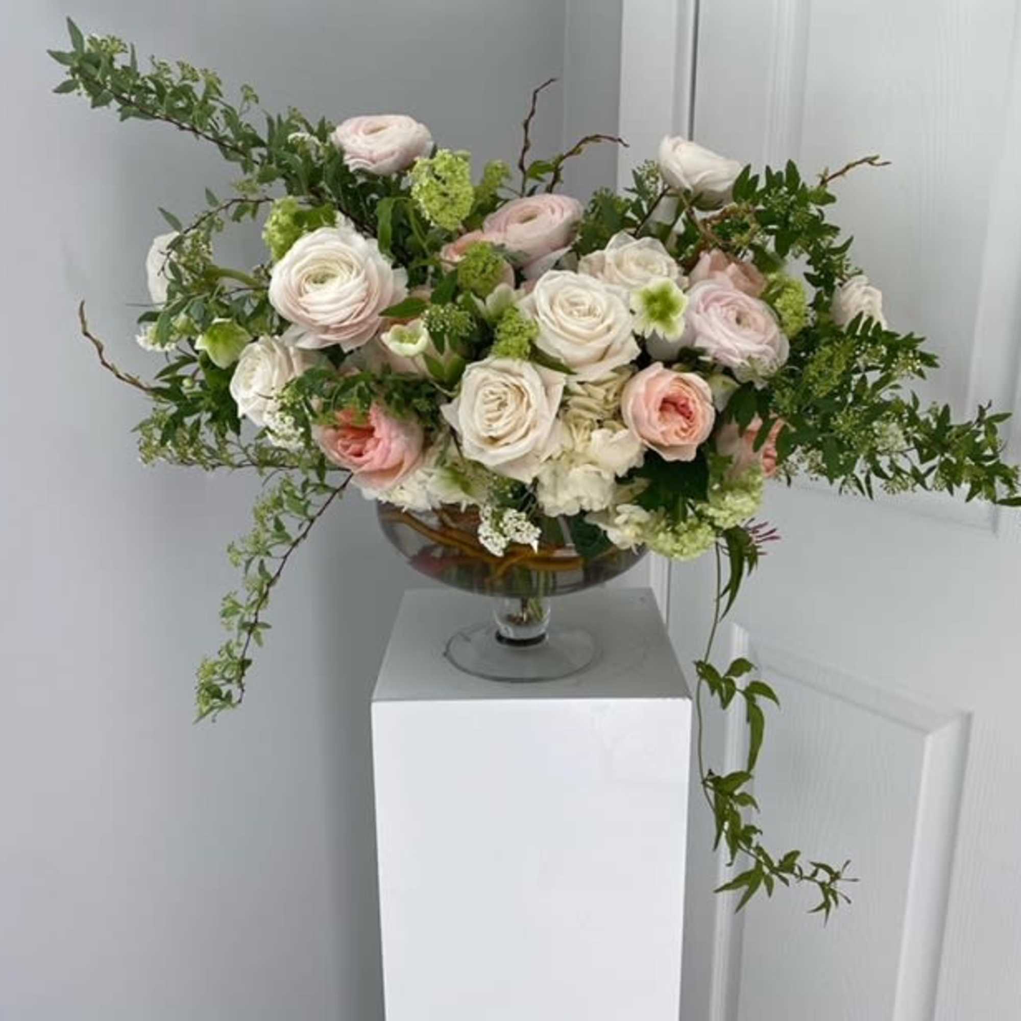 Pastel rose arrangement in a glass compote vase