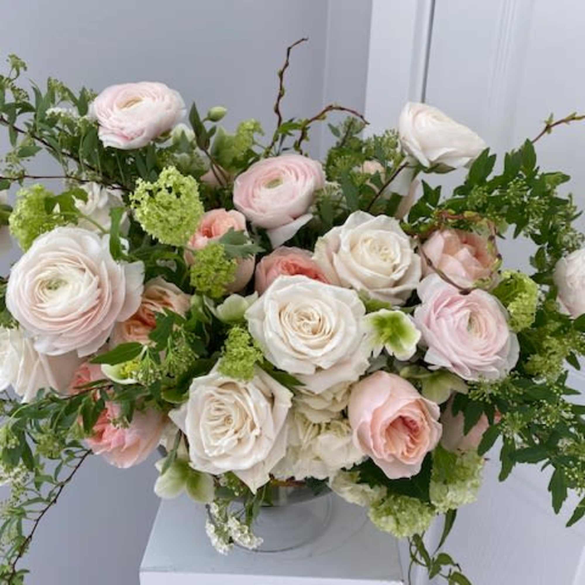 Blush and white roses with green filler in a clear vase