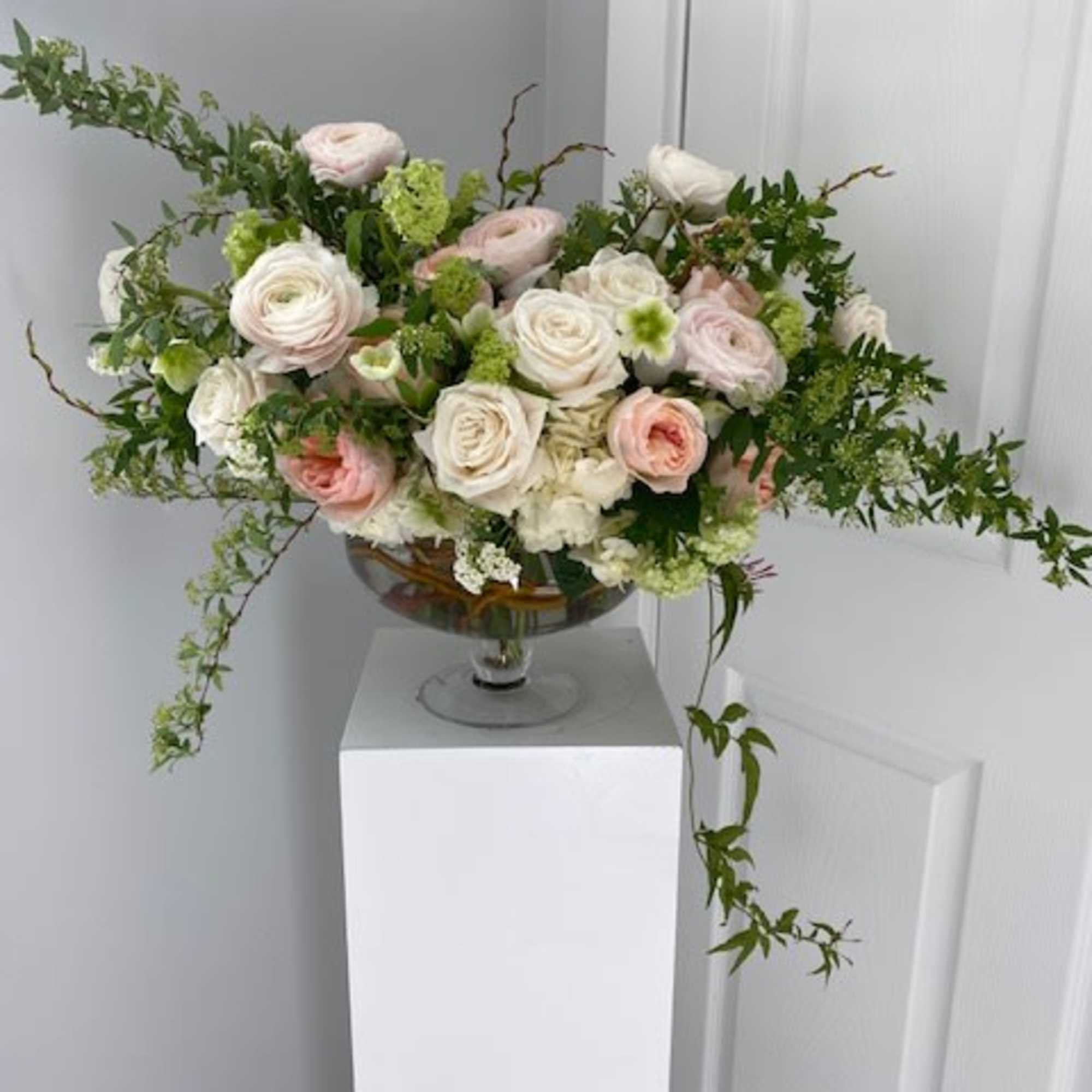 Arrangement of pale pink and white roses in a glass bowl vase