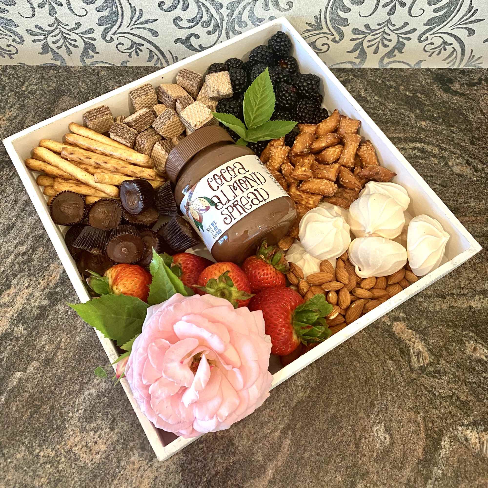 Gift box with snacks, strawberries, and a pink rose