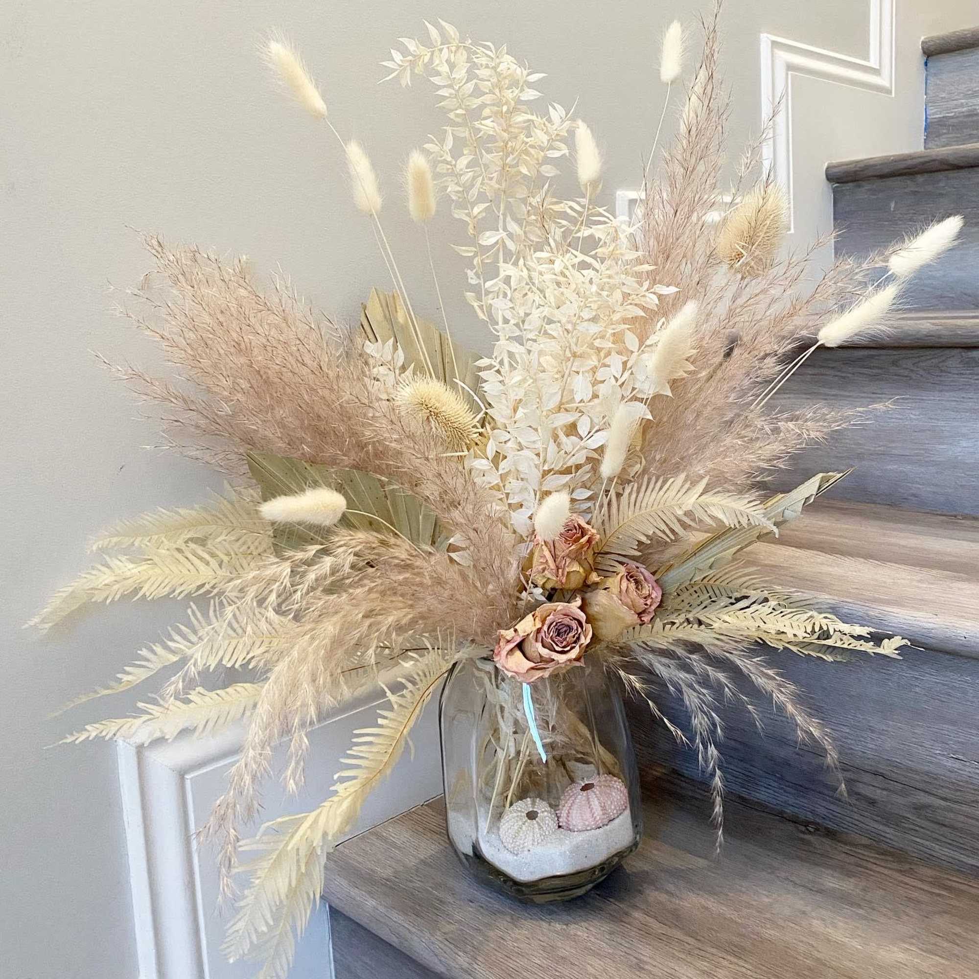 Dried floral arrangement in a glass vase with pale beige and blush accents