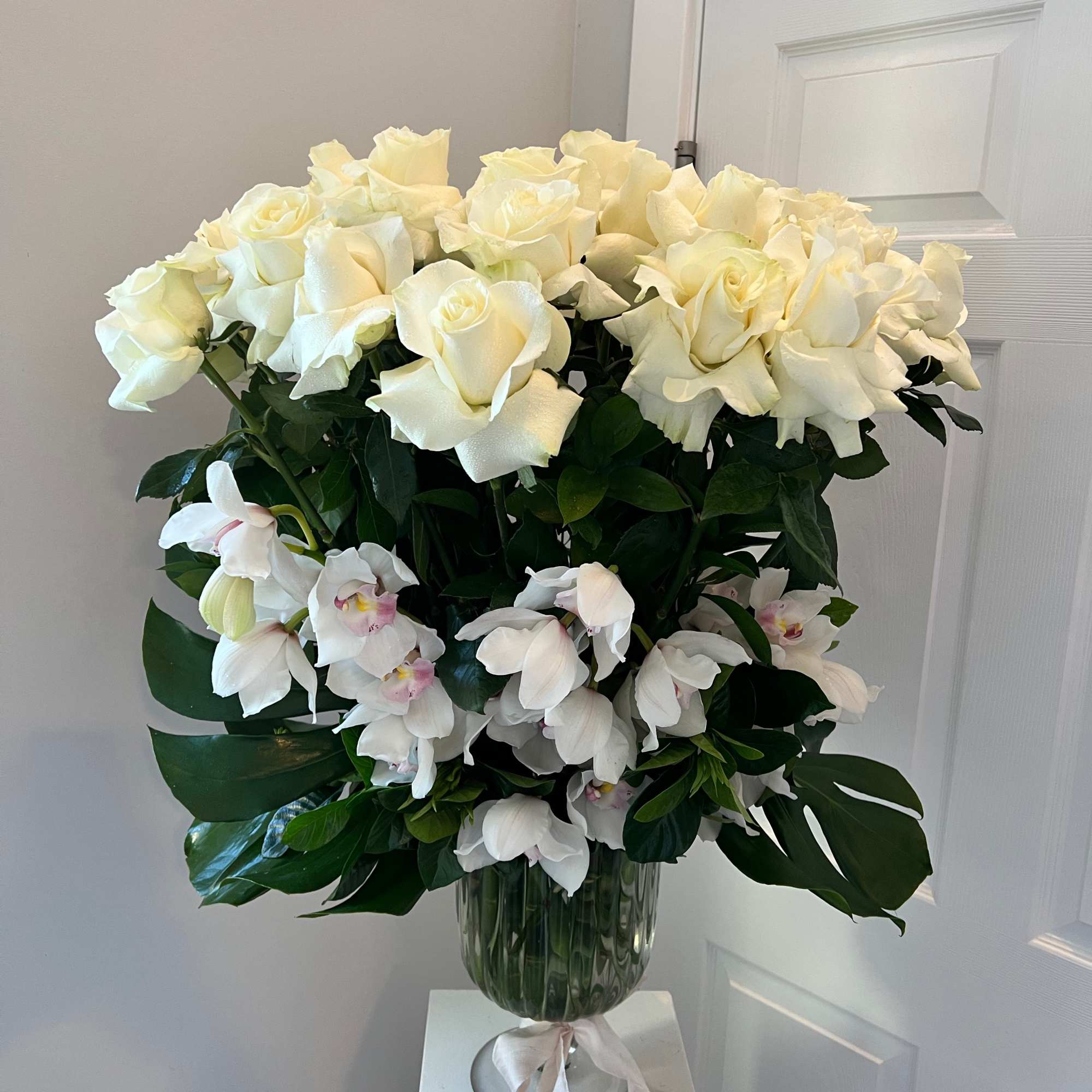 White roses and orchids arranged in a glass vase