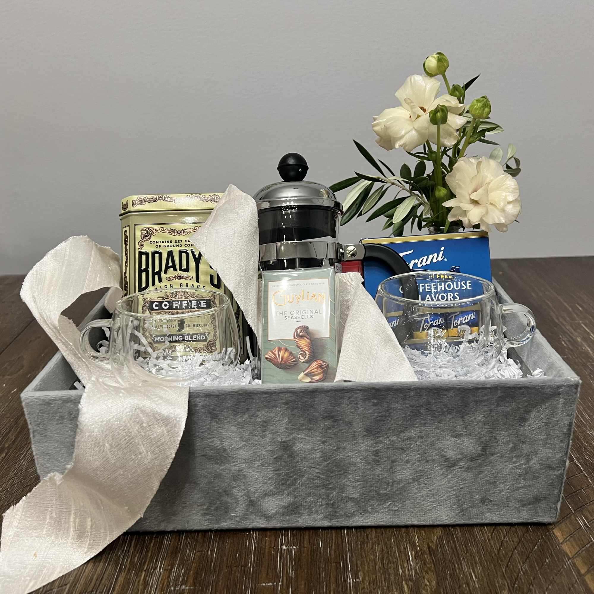 Gift basket with coffee, mugs, tea, and white flowers