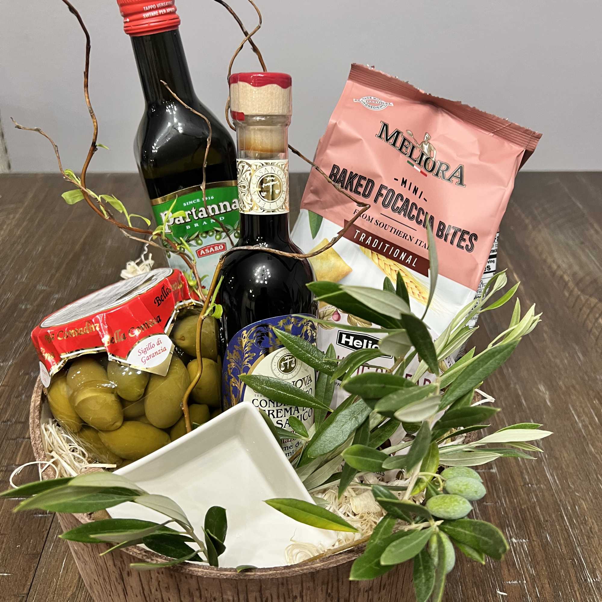 Gift basket with olive oil, olives, crackers, and a small dish