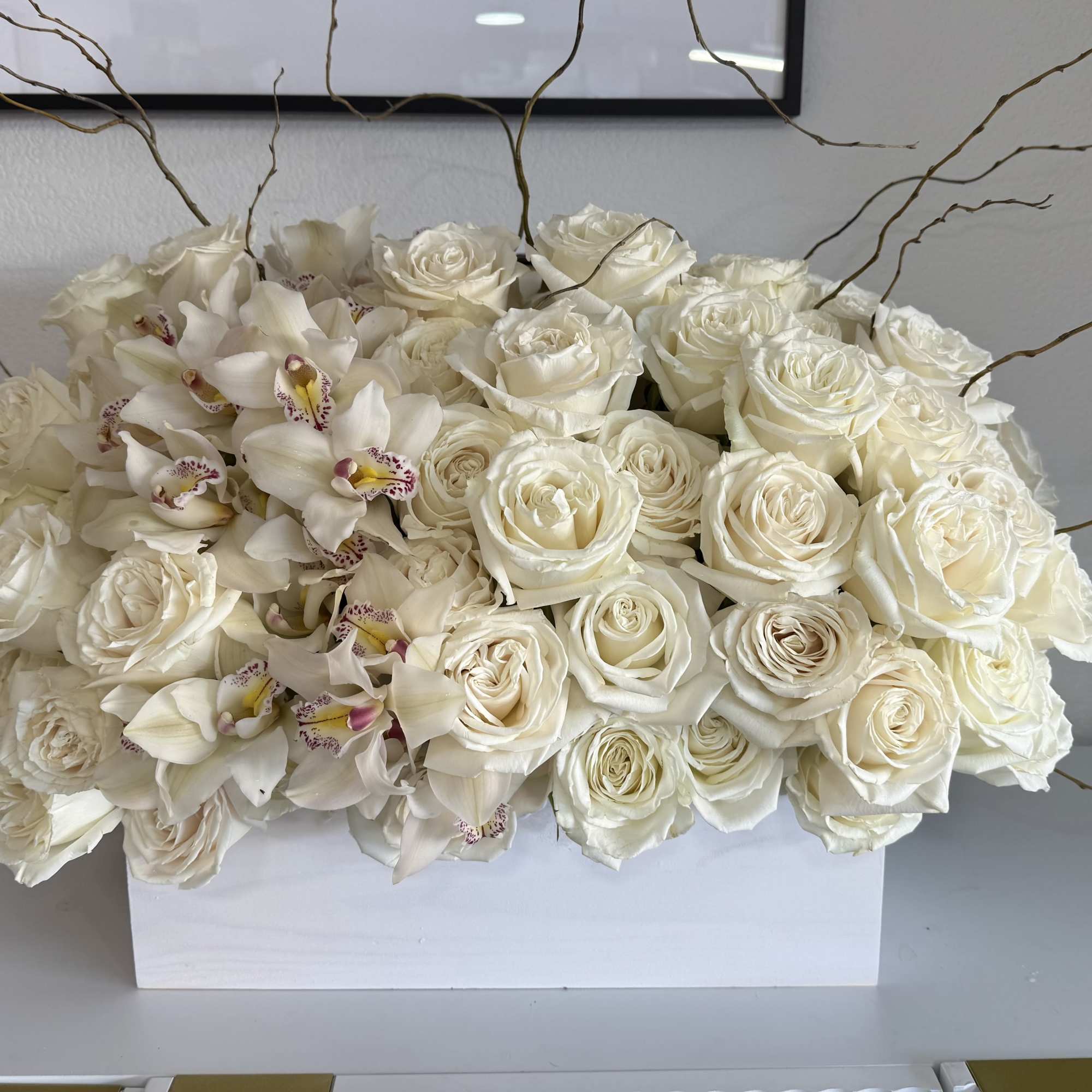 White roses and orchids arranged in a rectangular white box