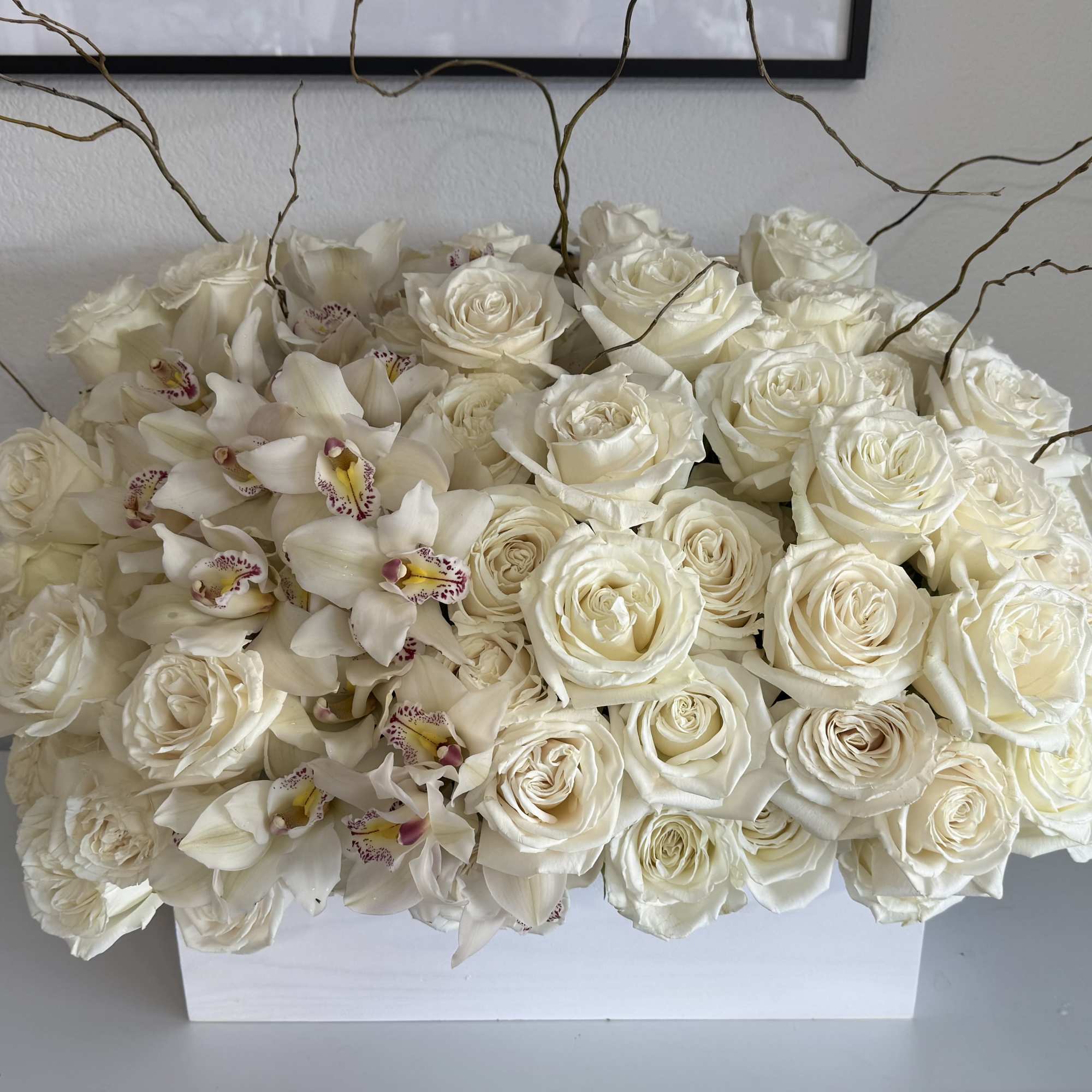 White roses and orchids arranged in a white rectangular box