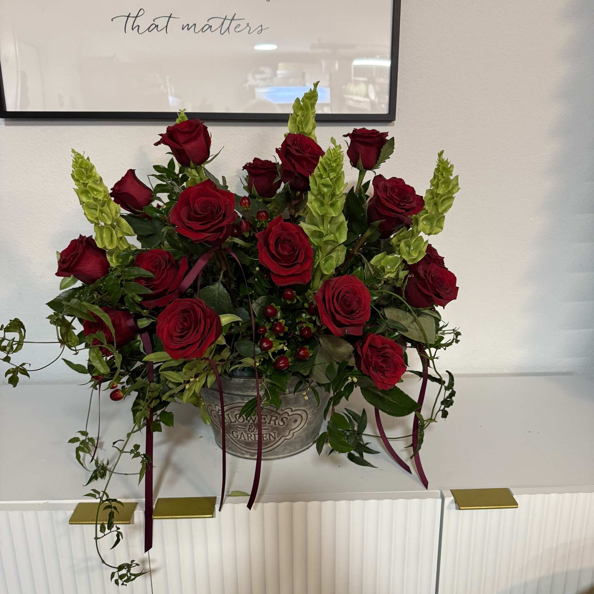 Red roses and green spikes arranged in a metal container