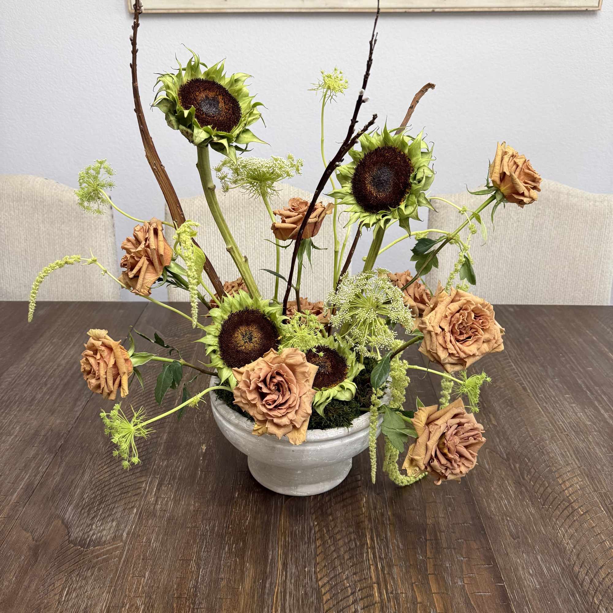 Sunflowers and peach roses arranged in a white bowl vase
