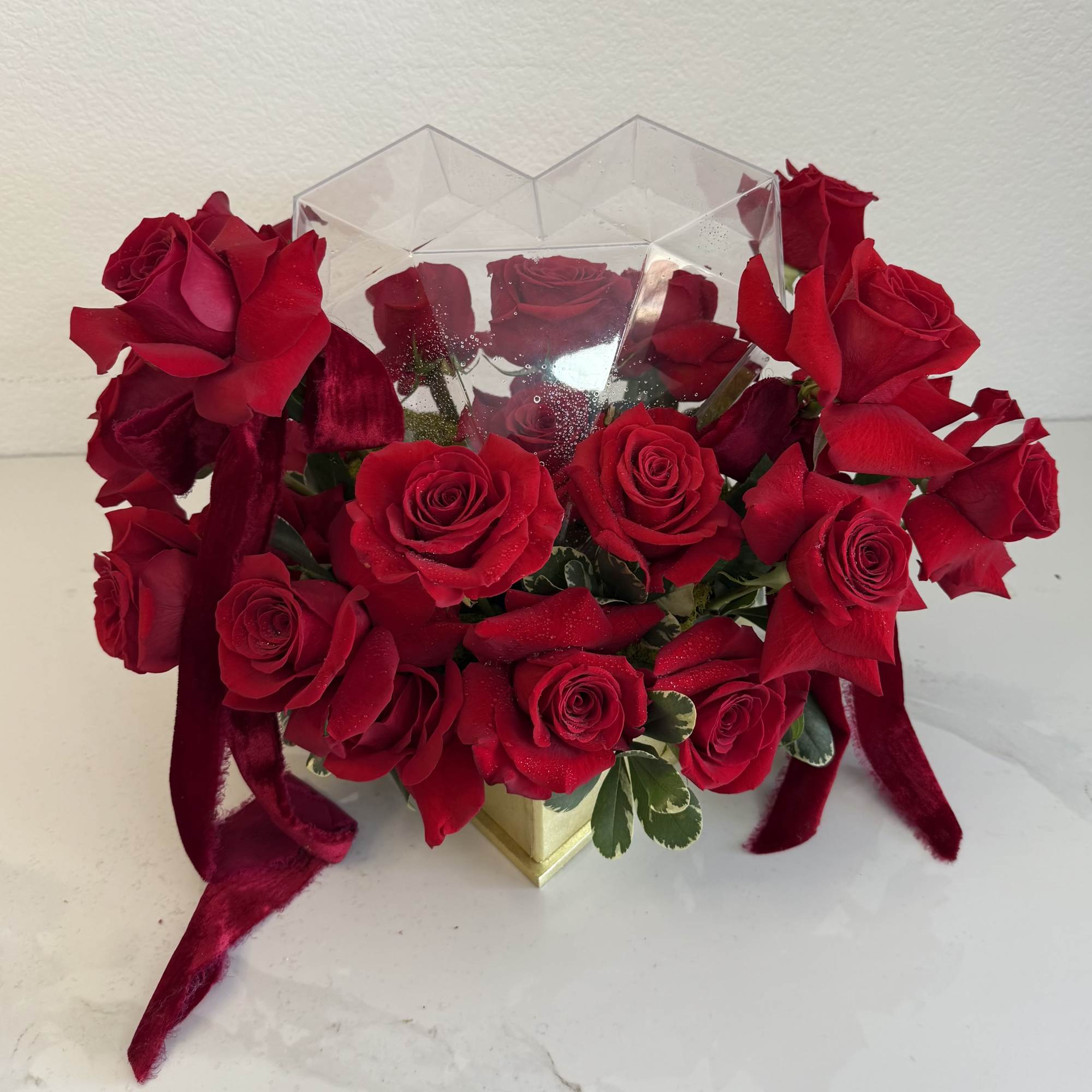 Bouquet of red roses in a clear geometric box with ribbon