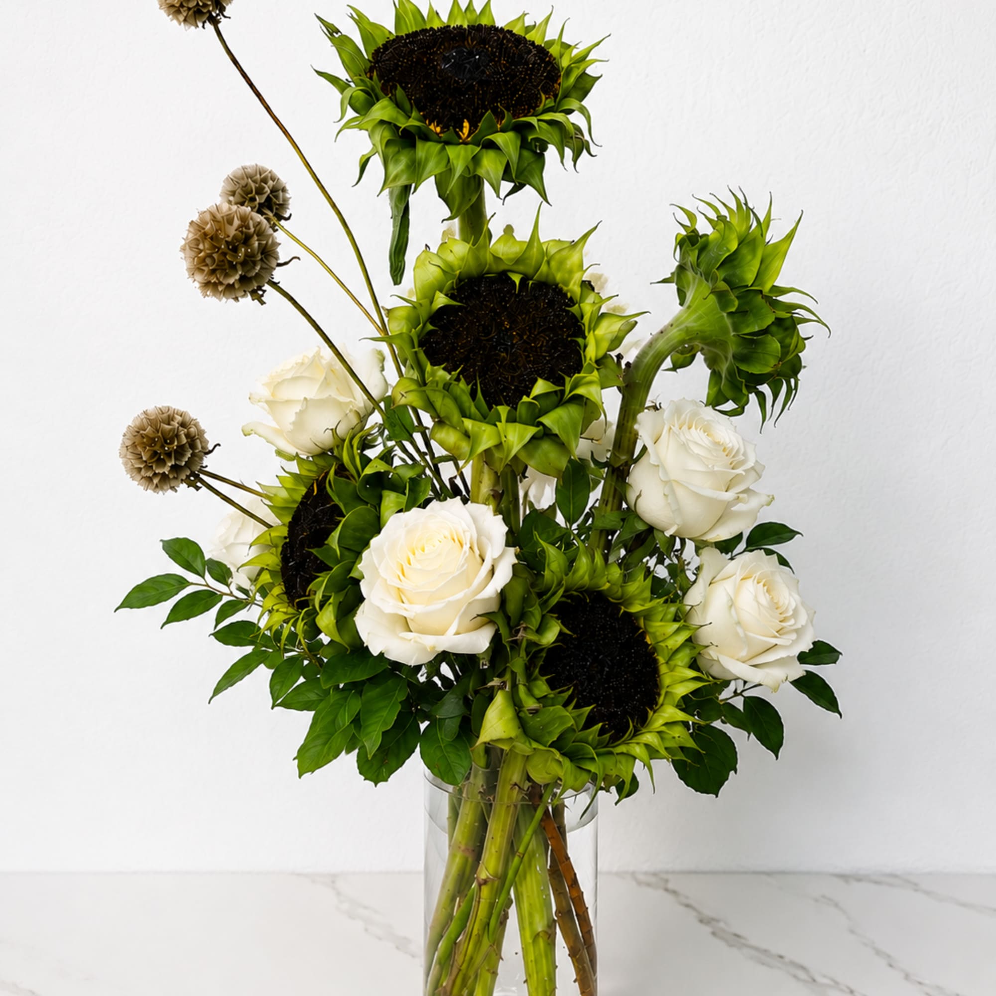Sunflowers and white roses arranged in a clear glass vase