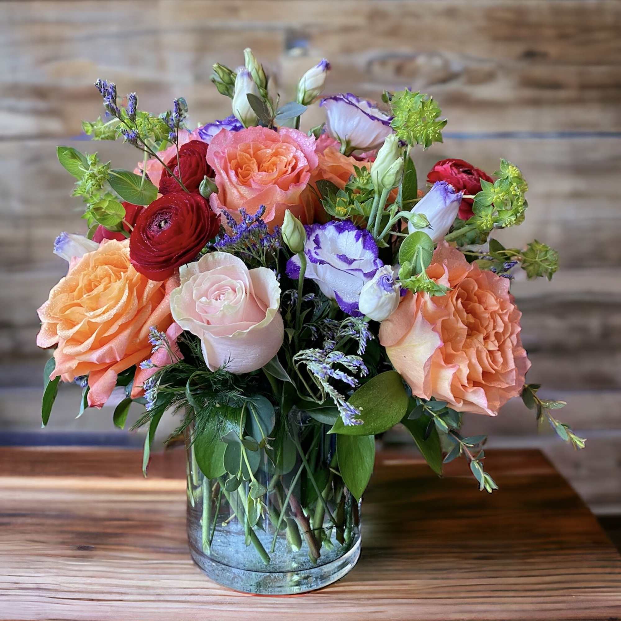 Mixed bouquet of roses and lisianthus in a clear glass vase