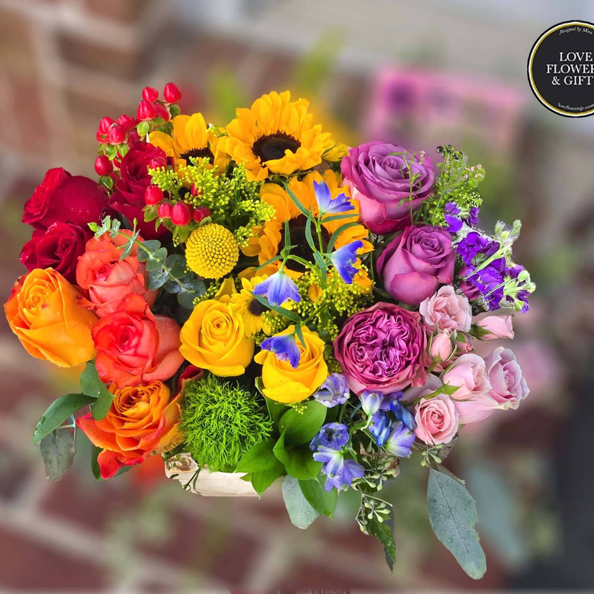 Bright mixed bouquet with yellow sunflowers, multicolor roses, and purple and blue accent flowers