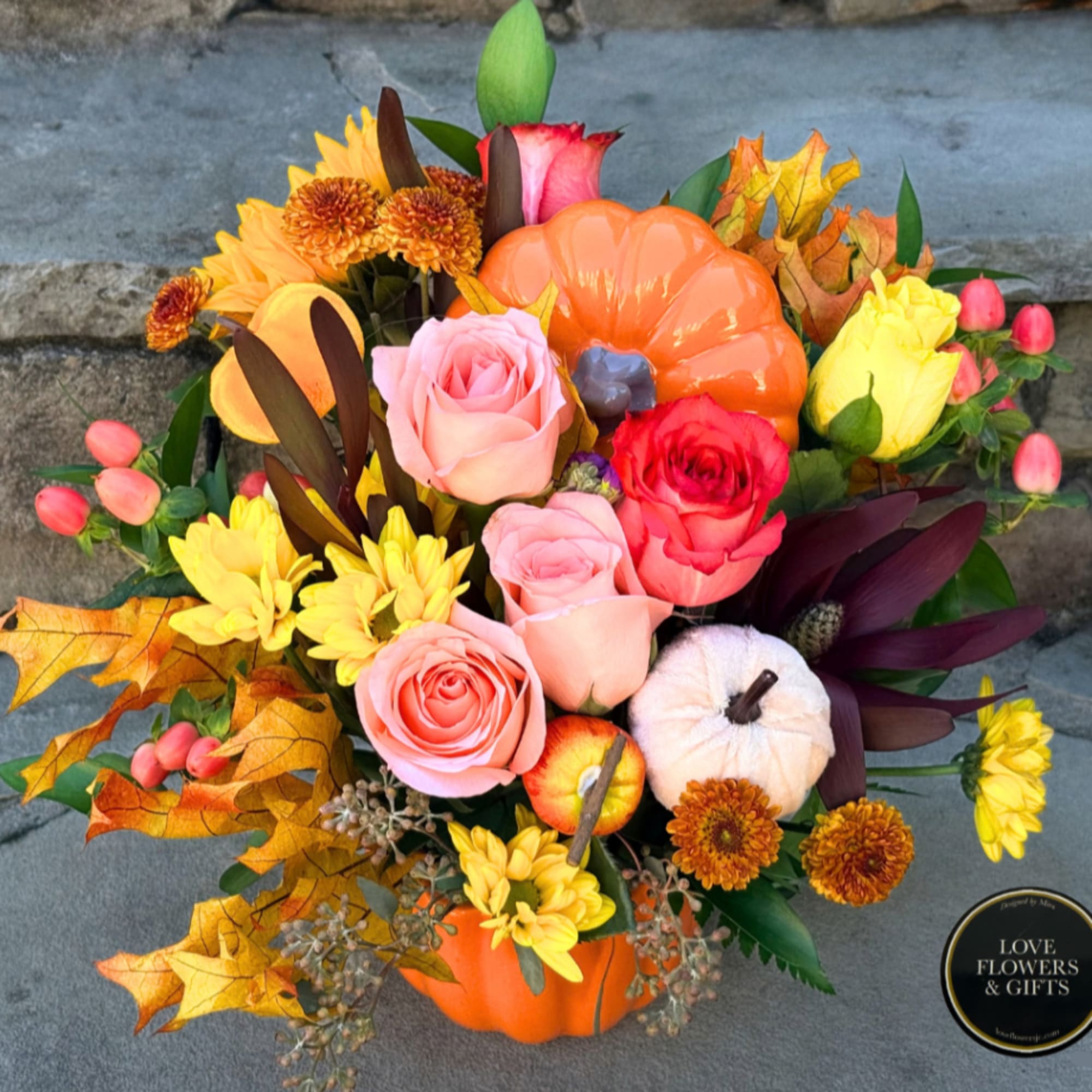 Autumn floral arrangement in a pumpkin container with roses and mums