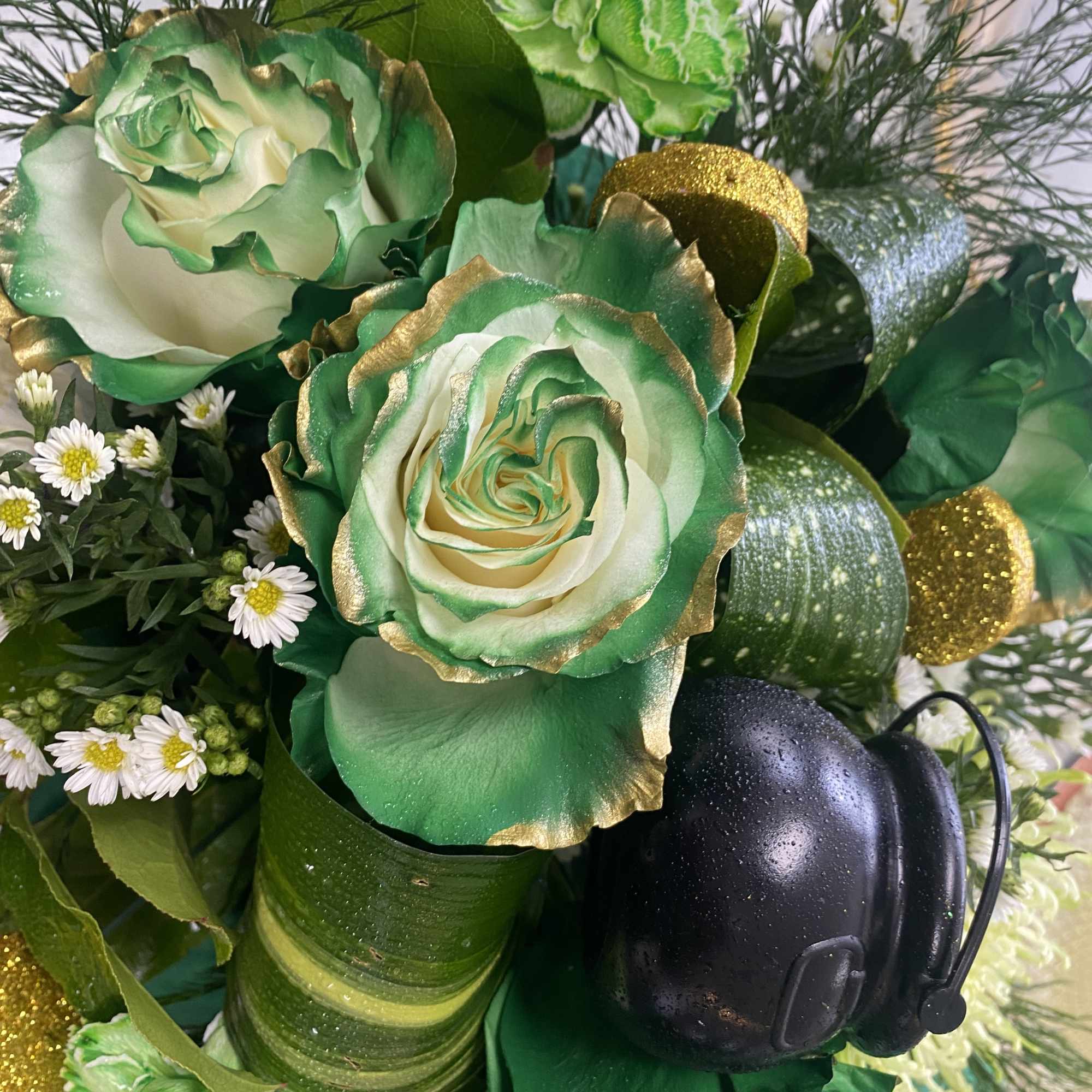 Green and white floral arrangement with gold accents and a black firefighter helmet