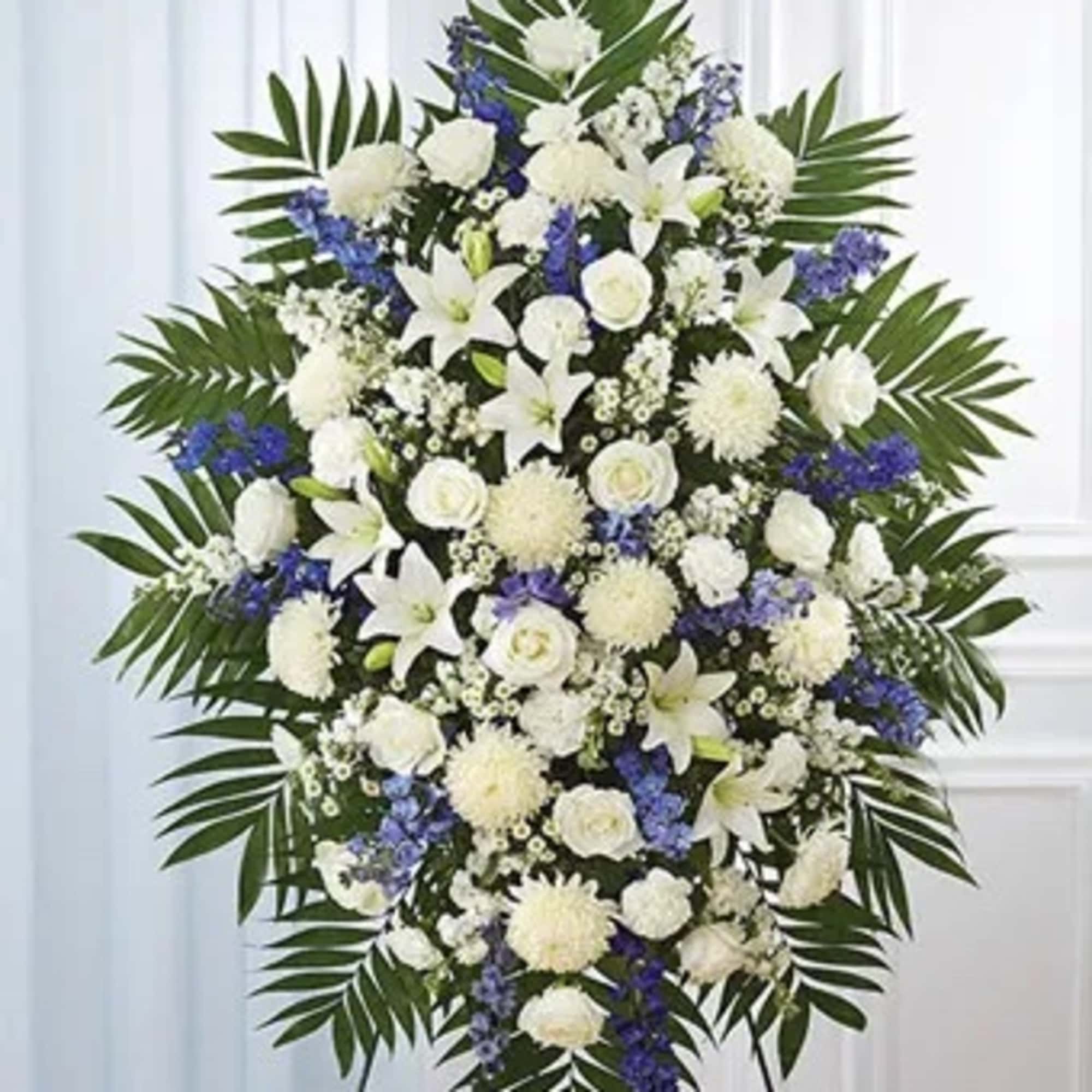 Standing funeral spray of white and blue flowers on a display easel
