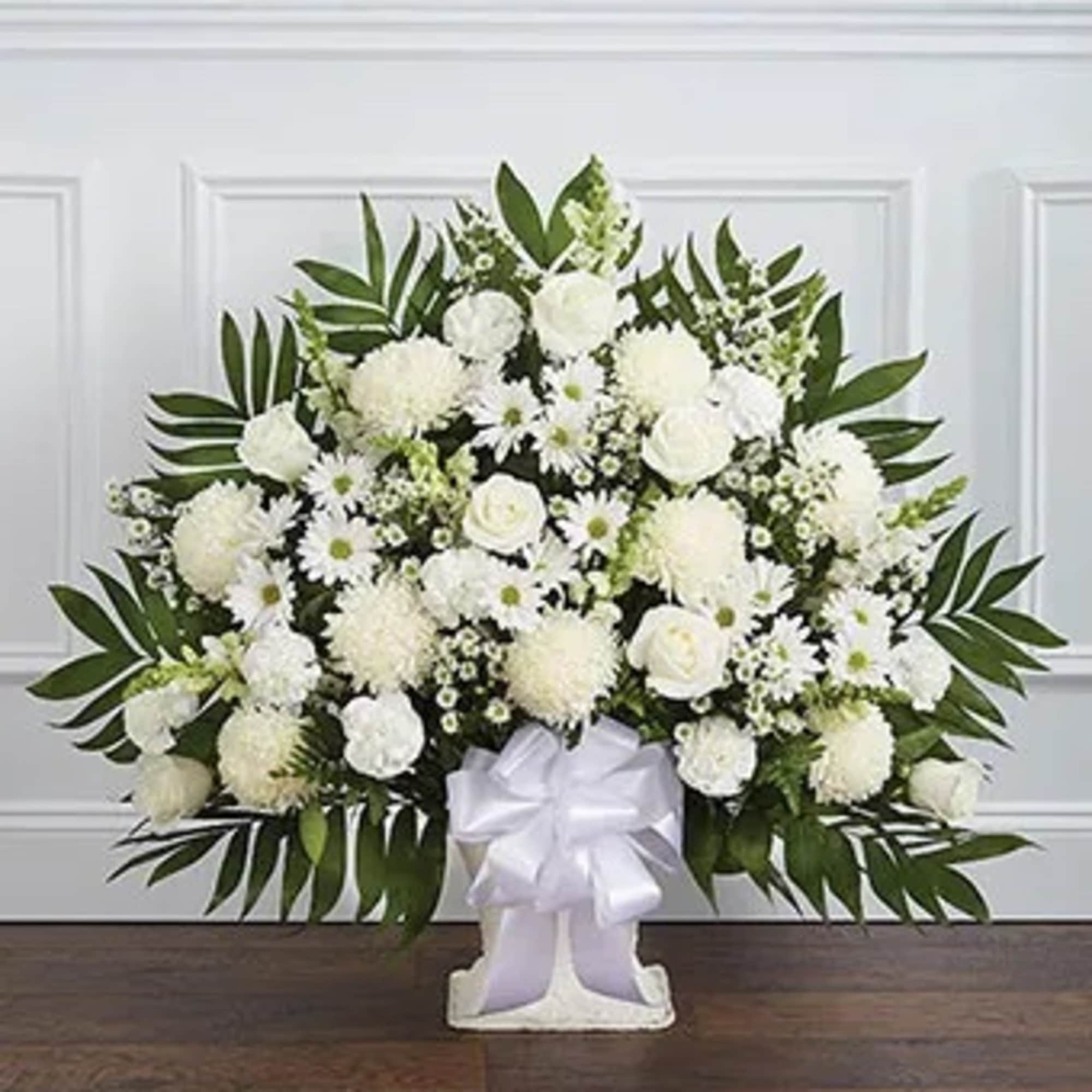 White floral standing spray with a white ribbon on a stand