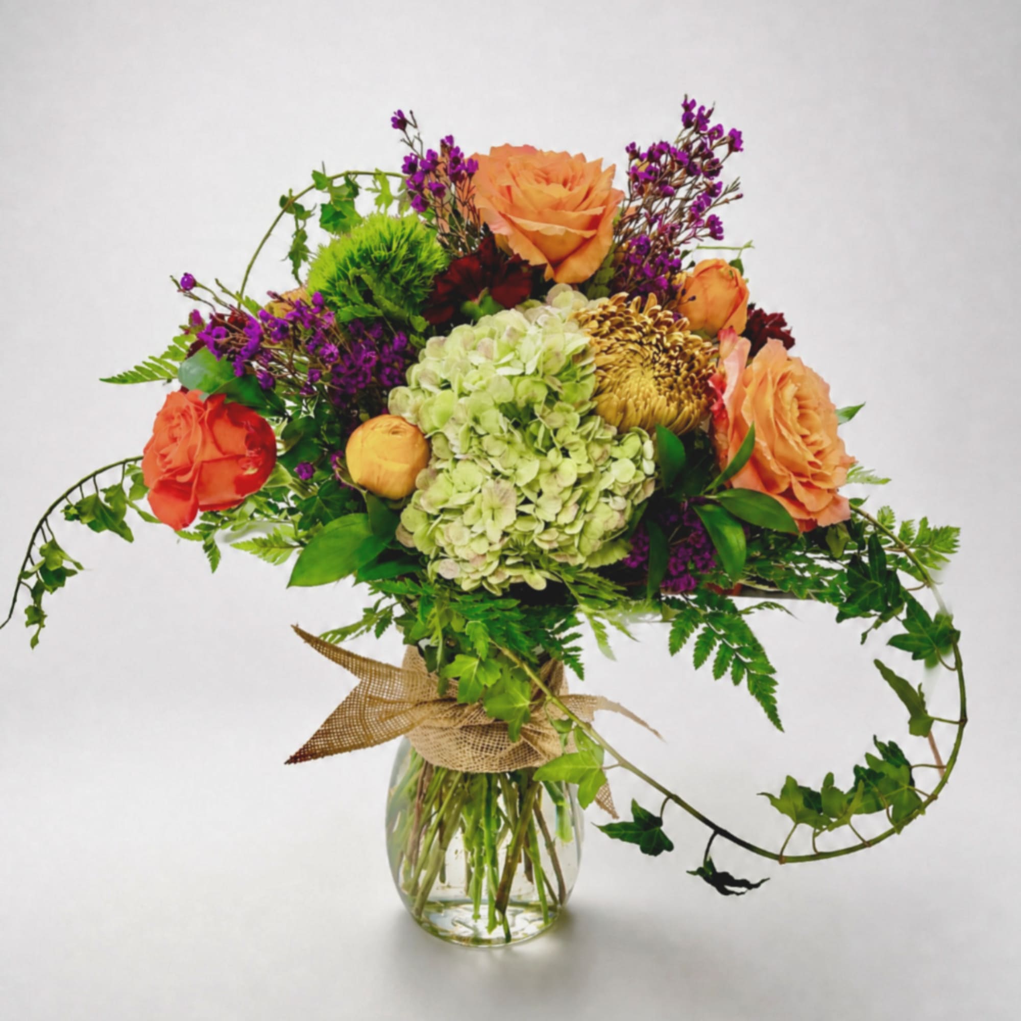 Bouquet of orange and purple flowers in a clear glass vase