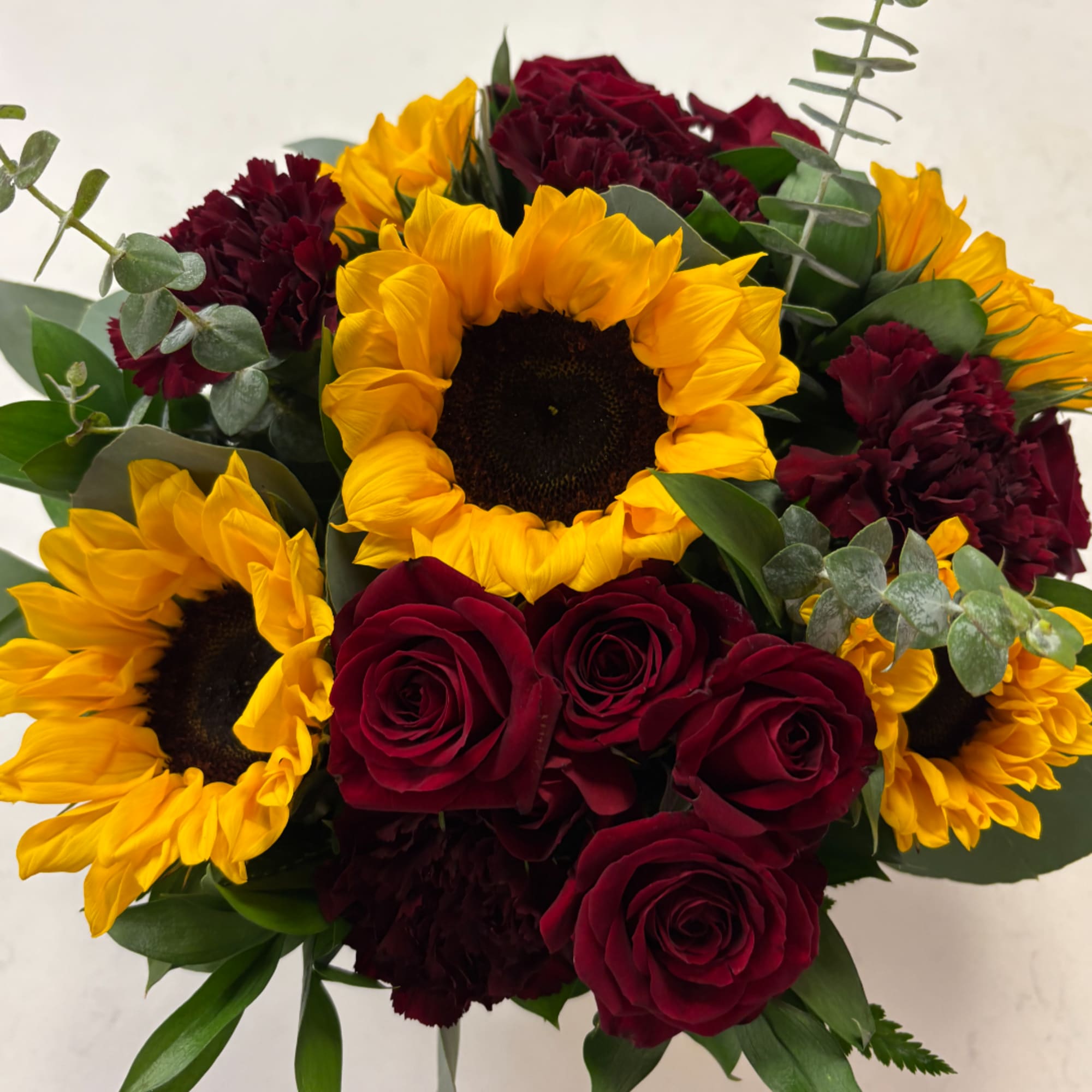 Bouquet of yellow sunflowers and deep red roses with dark red carnations