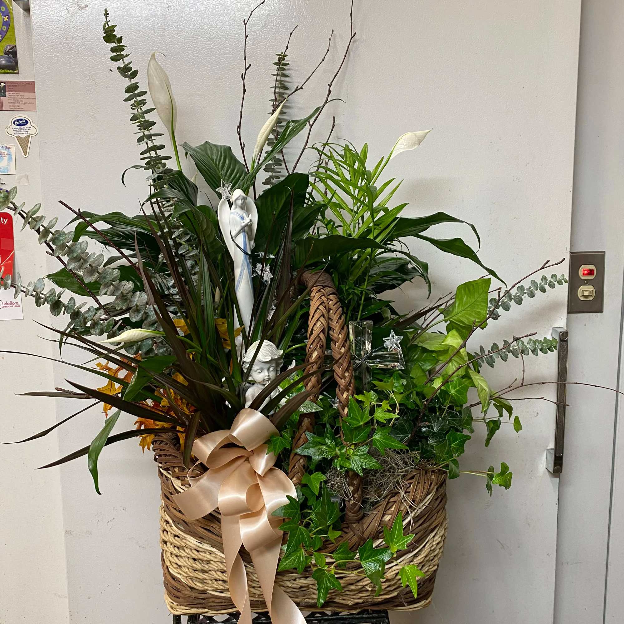 Basket arrangement with white calla lilies, greenery, and a satin bow