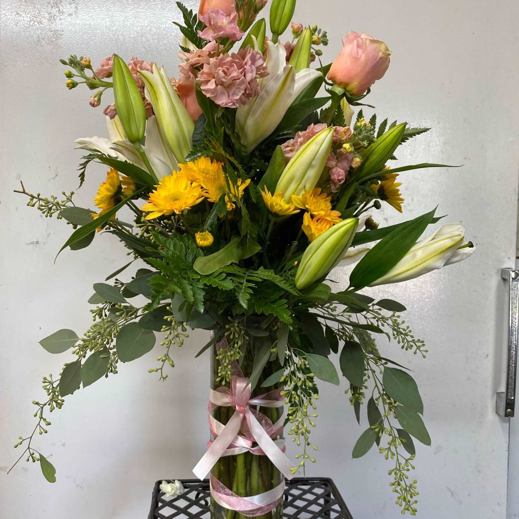 Pink roses and lilies in a glass vase with ribbon