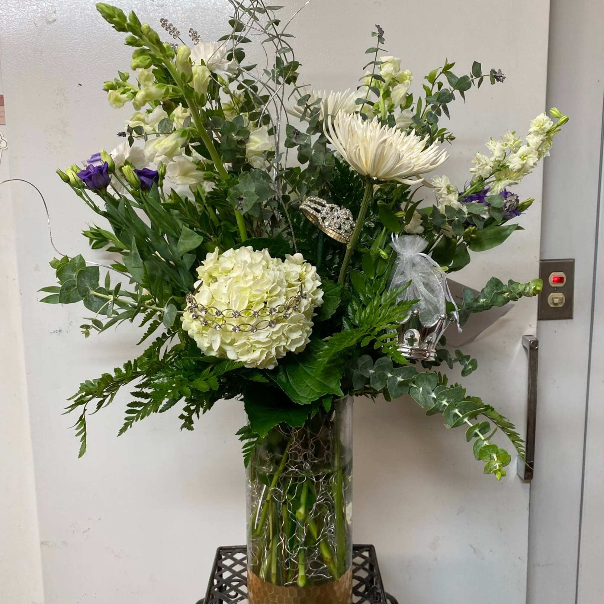 Tall white and purple floral arrangement in a glass vase